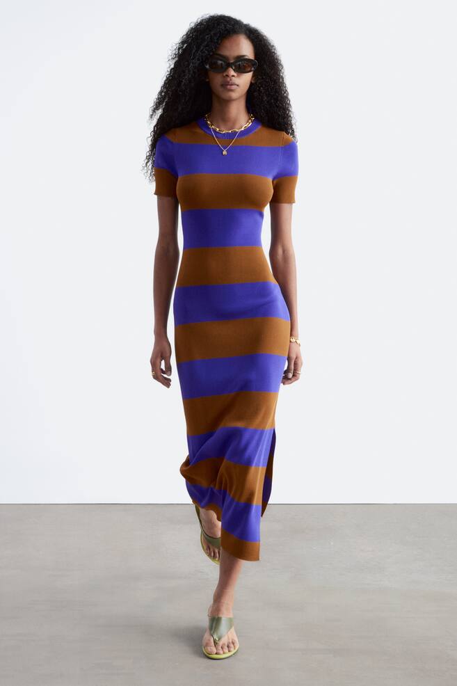 Een midi-jurk met afwisselende horizontale strepen in warm bruin en levendig blauw-paars. Het is gesneden met korte mouwen en een ronde halslijn, terwijl het een aansluitend silhouet presenteert met een zij-split nabij de zoom. - 1