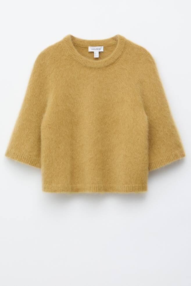 The golden yellow knitted T-shirt is displayed from the FRONT, showcasing a brushed, fuzzy texture and a loose silhouette. It is designed with a round neckline, ribbed trims at the neckline, hem, and cuffs, and sleeves that finish just above the elbows. - 1