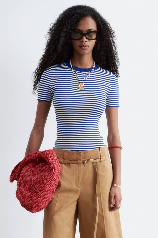 The blue and white striped short-sleeved top boasts a ribbed knit texture, a blue ribbed crew neck, and blue ribbed cuffs on its short sleeves, offering a snug fit. - 1