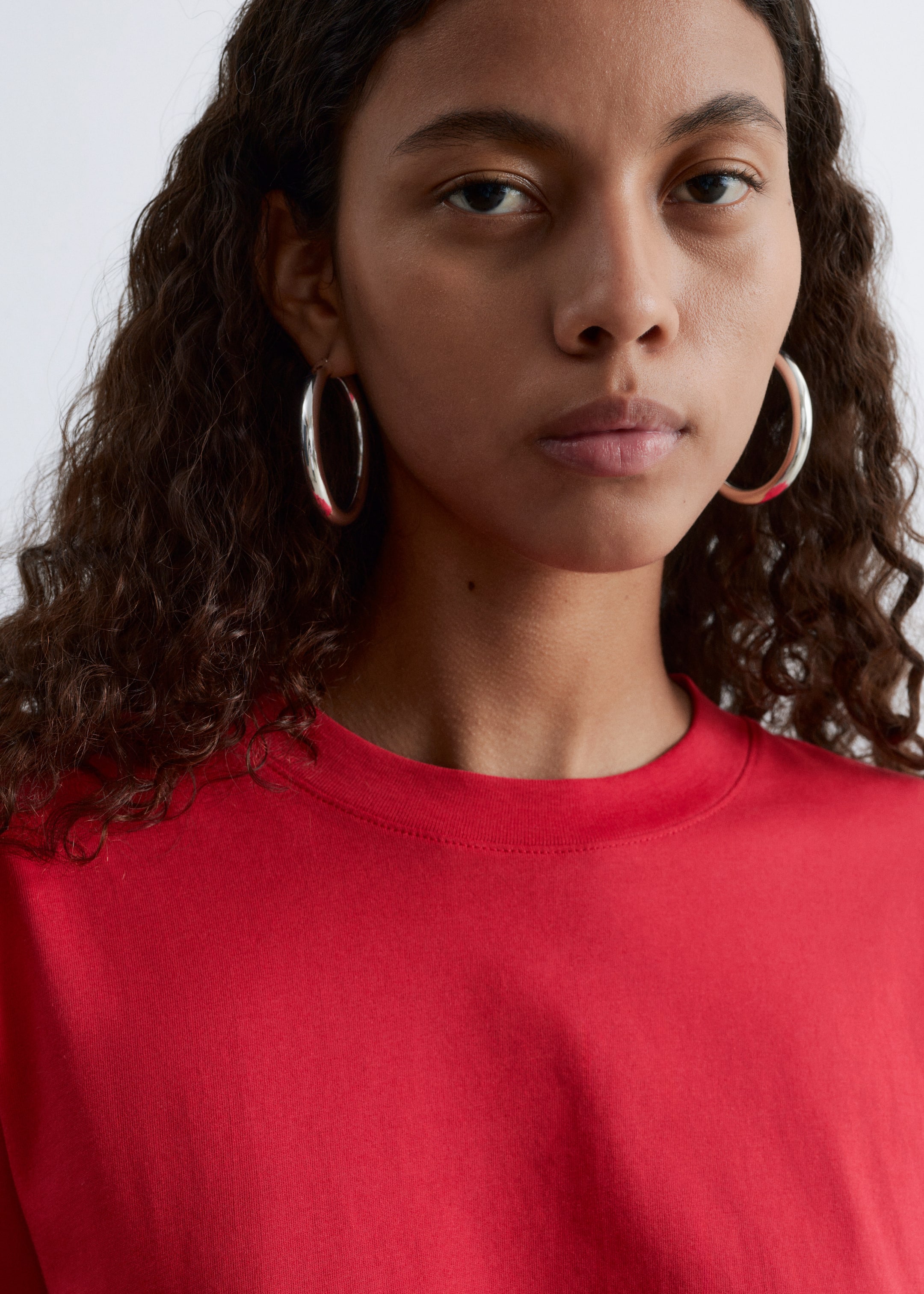View larger image: A red t-shirt is featuring a round, ribbed neckline. It is presenting a slightly angled front view, fitting smoothly across the upper chest and shoulders.