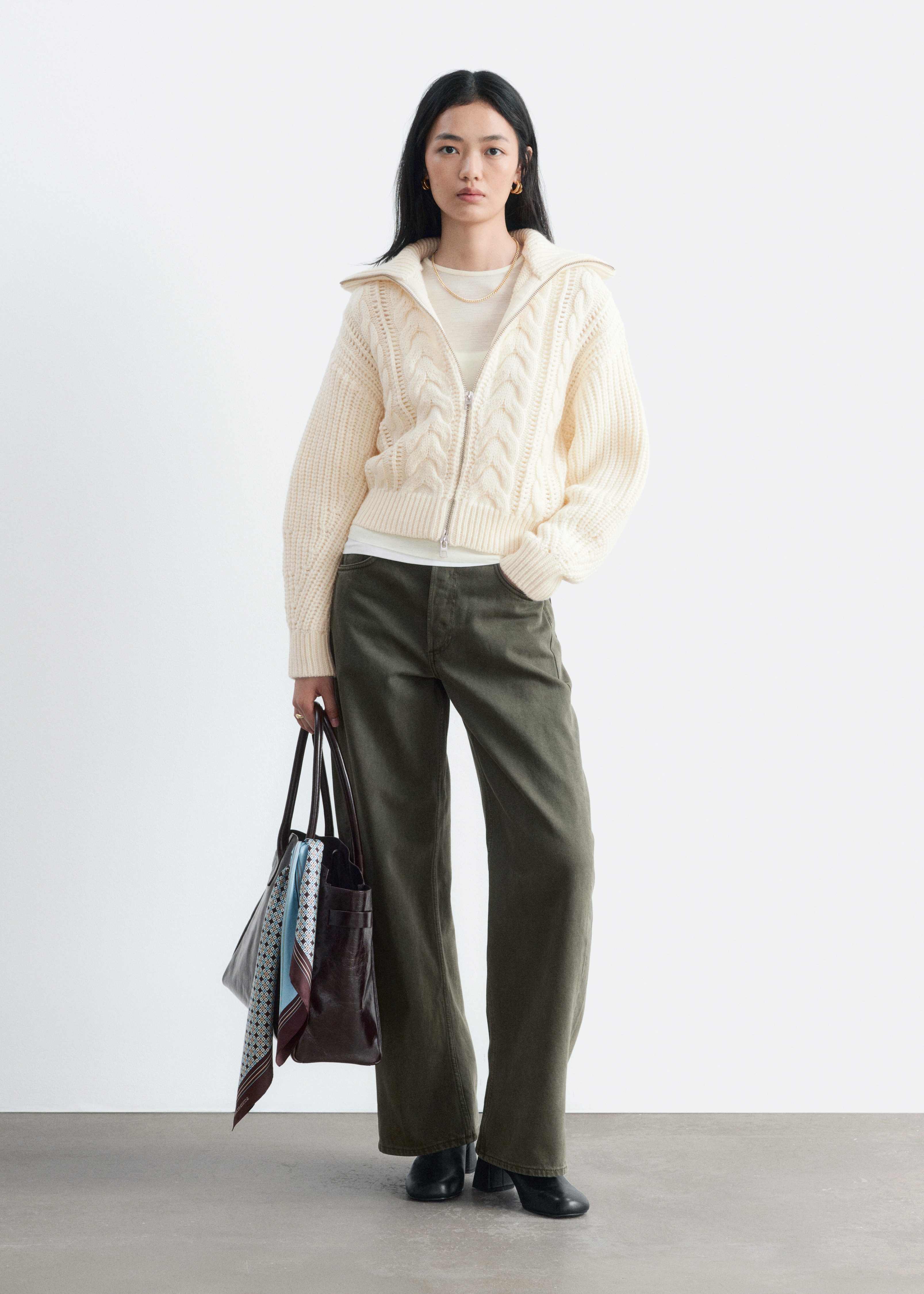 Estes jeans verde-azeitona sÃ£o apresentados de frente, com um design clÃ¡ssico de cinco bolsos, cintura de altura mÃ©dia, corte oversized e pernas em formato barrel, rematadas com bainhas dobadas.
