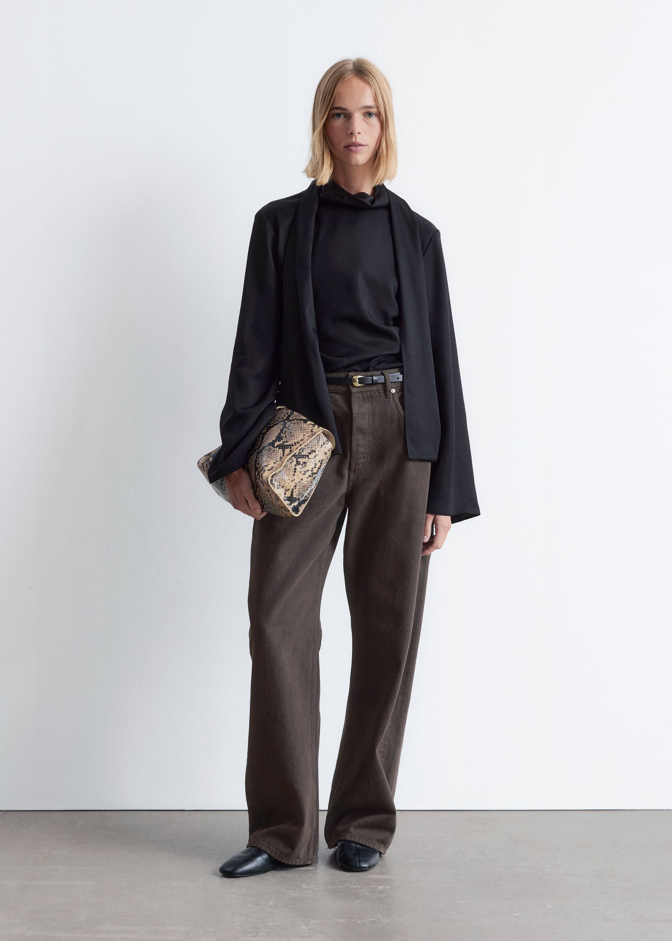 Agrandir l'image: Le produit est un ensemble orienté vers l'avant, présentant une veste noire ouverte sur le devant superposée à un haut noir à col montant. Un pantalon large marron foncé est porté avec une fine ceinture noire, et des chaussures plates noires complètent le look, tandis qu'une pochette rectangulaire à motif peau de serpent est tenue.