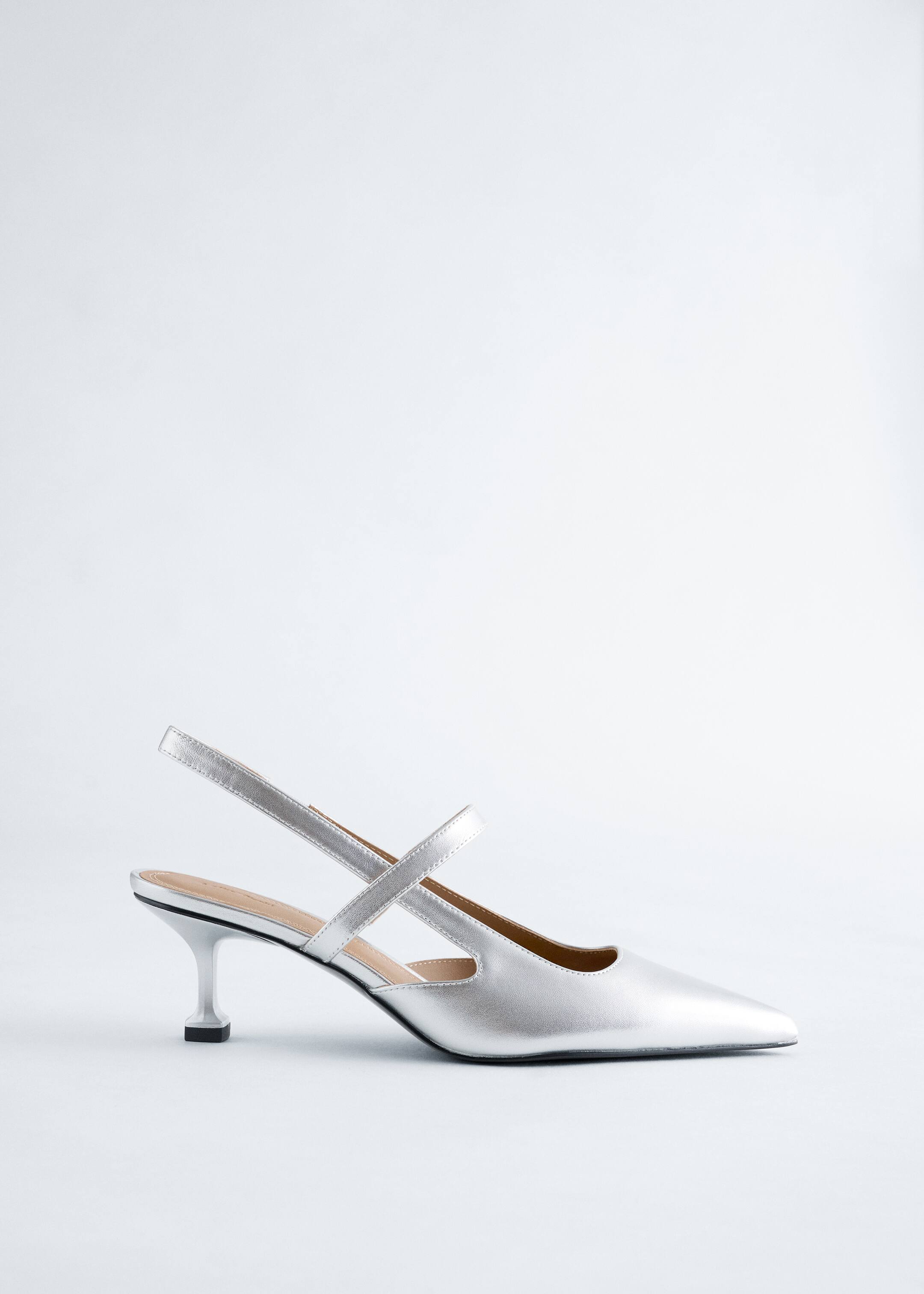 Agrandir l'image: Une chaussure slingback à bout pointu argentée est orientée vers la gauche, avec un talon bas évasé et deux brides croisées sur le cou-de-pied.