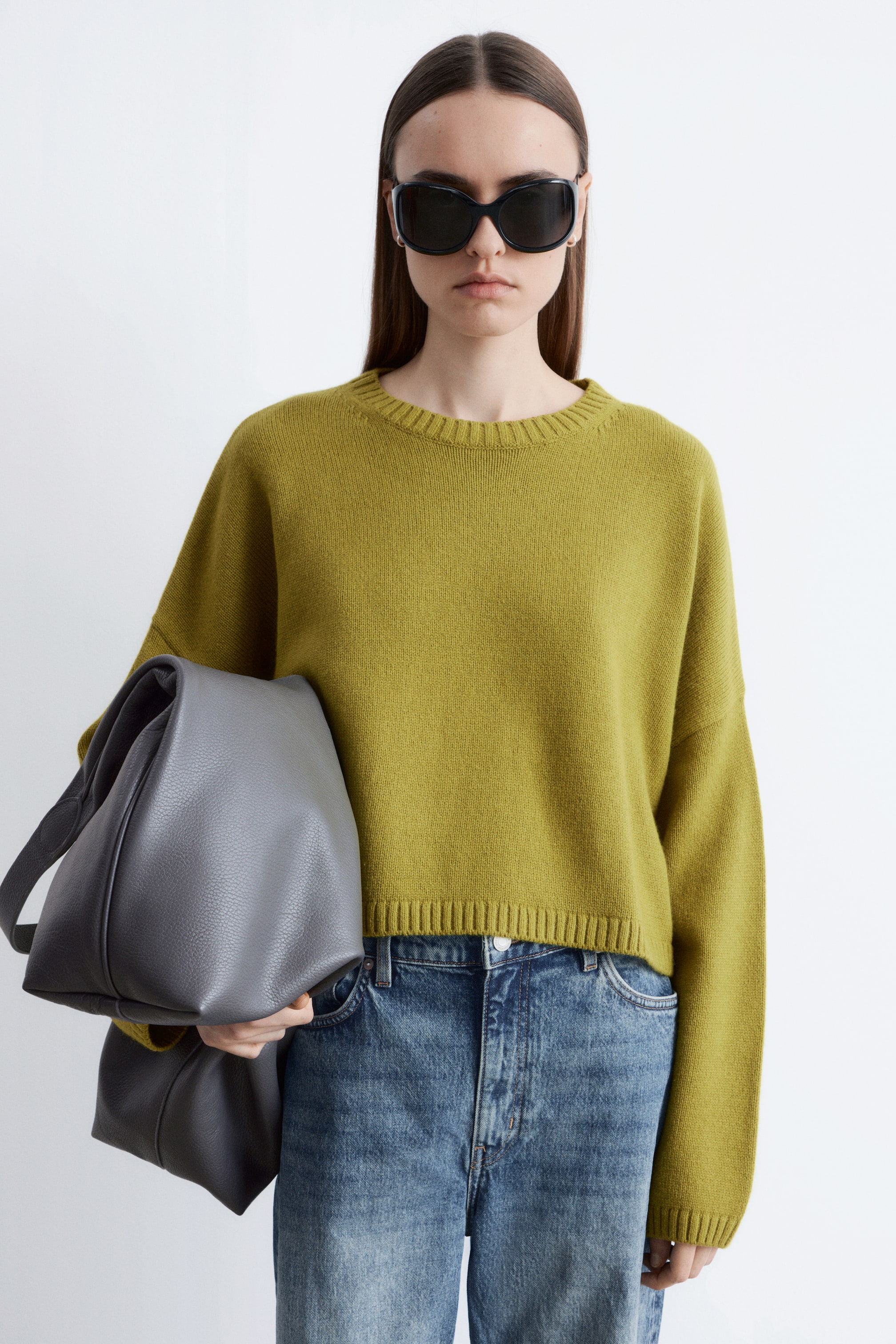 Se større billede: En chartreuse-grøn crewneck-sweater præsenteres med en afslappet pasform, sænkede skuldre, lange ærmer med ribstrikkede manchetter og en kort, ribstrikket kant.