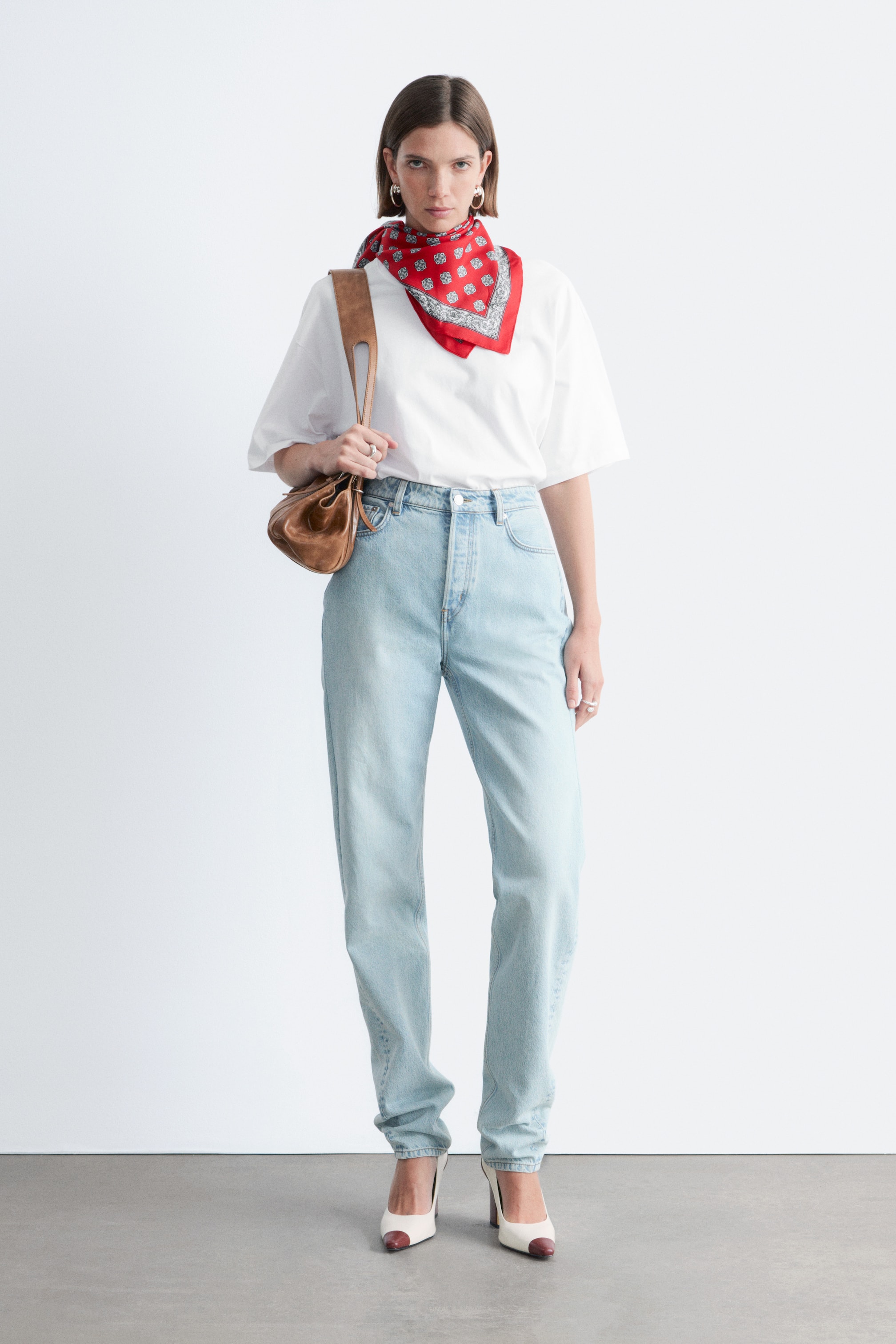 Zobraziť väčší obrázok: Červená štvorcová šatka je uviazaná okolo krku, s bielym a sivým vzorovaným lemom a opakujúcimi sa centrálnymi motívmi.