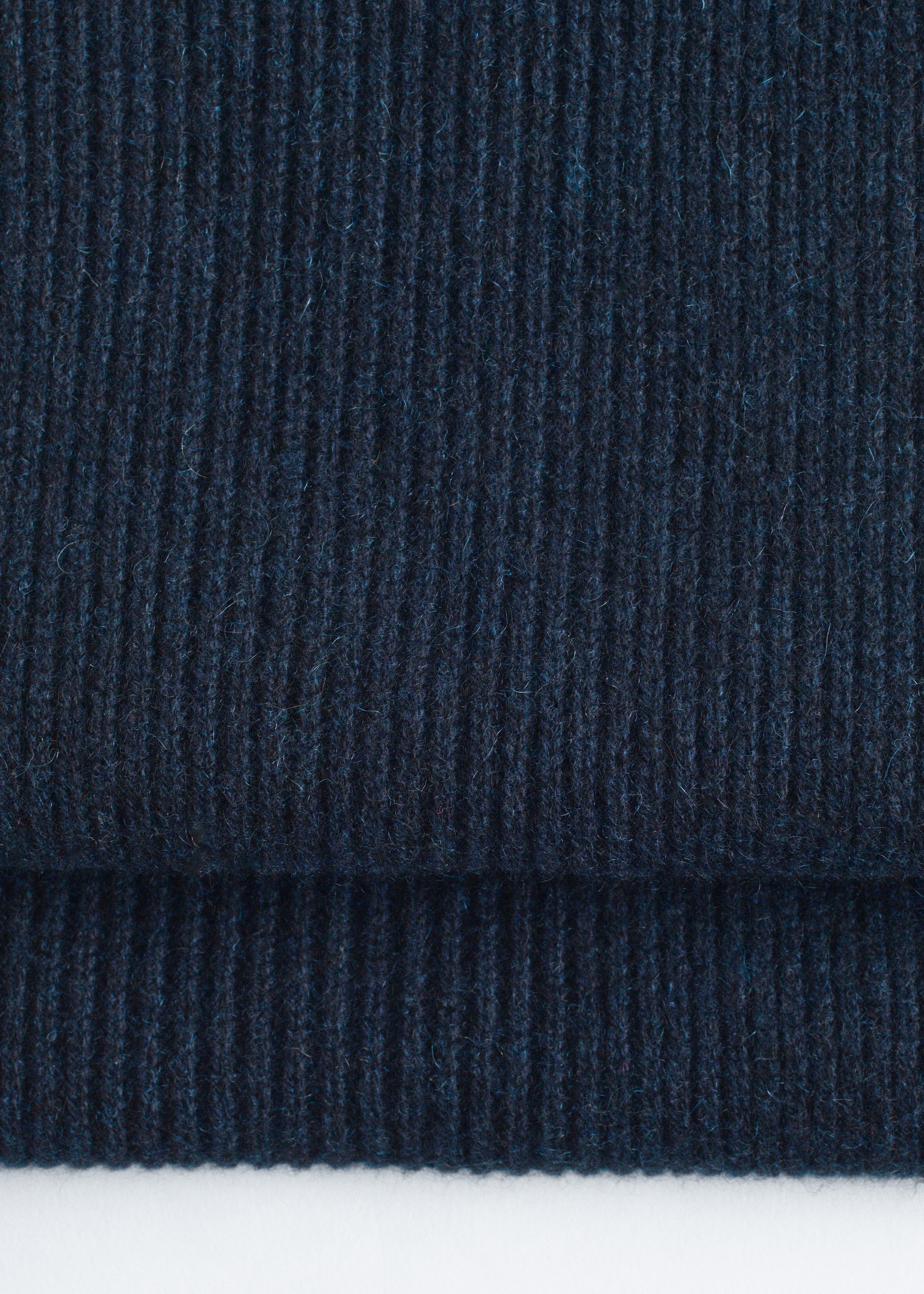 Größeres Bild ansehen: Ein dunkelblauer gerippter Kaschmirstrickschal zeigt seine Textur in einer Nahaufnahme von vorne, mit einer horizontalen Falte am unteren Rand.