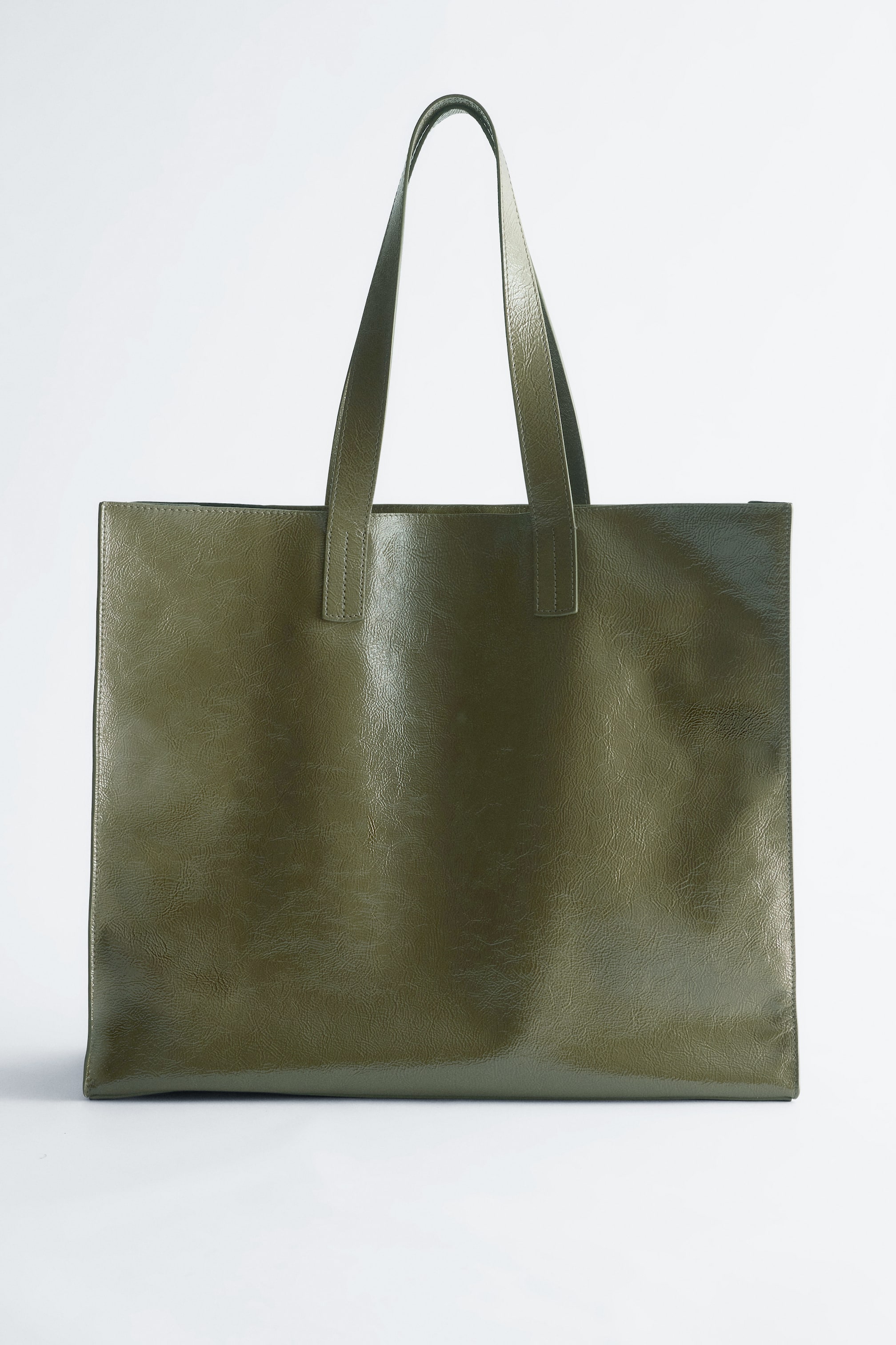 Grotere afbeelding bekijken: Een donker olijfgroene tote bag is naar VOREN gericht, met een rechthoekige, minimalistische vorm. Het is gemaakt van een getextureerd, licht glanzend leer, en twee dunne bovenhandvatten strekken zich uit vanaf de bovenrand.