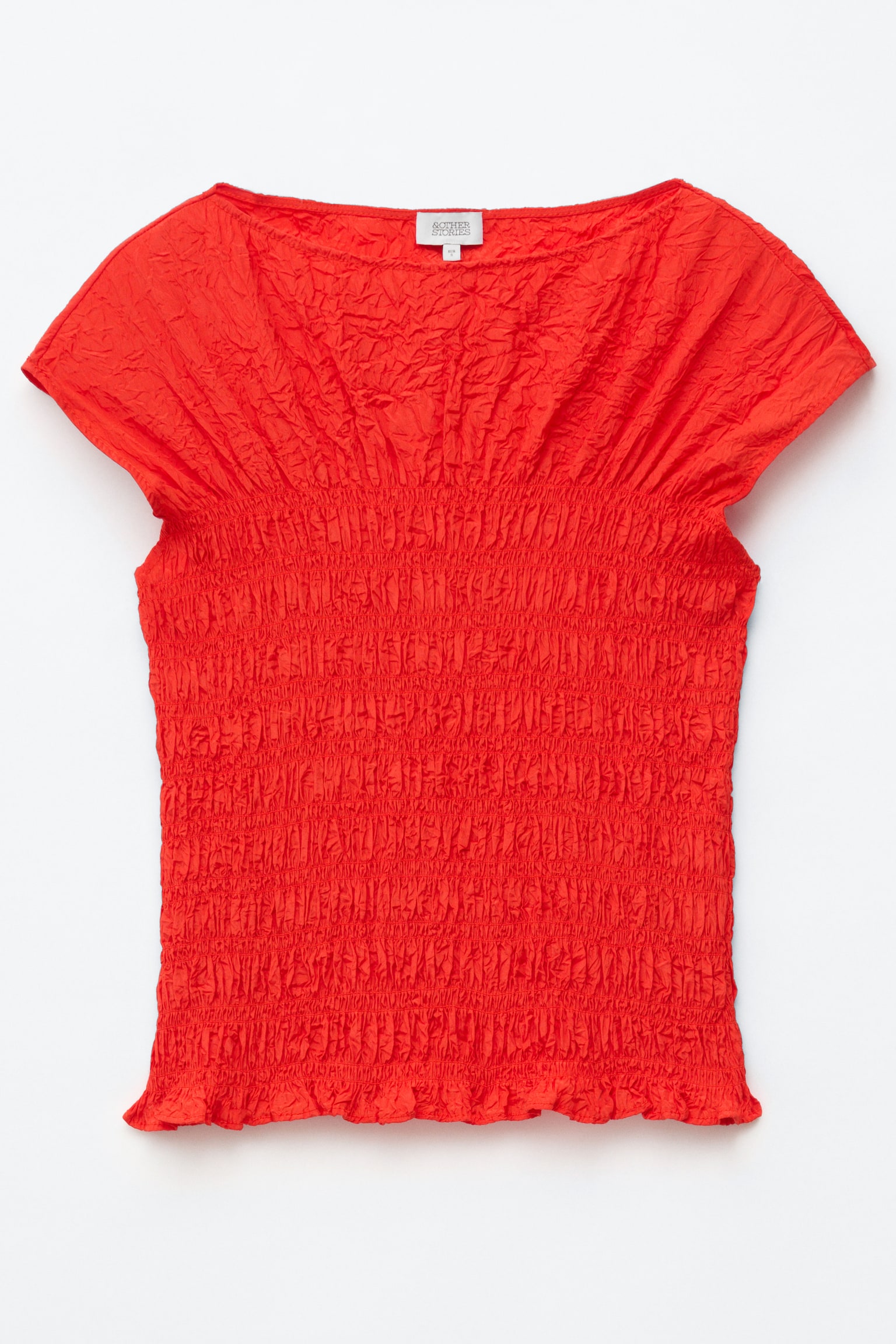 Um top vermelho é mostrado de frente, apresentando uma textura jacquard enrugada, decote barco, mangas curtas e um corpo justo e franzido. - 1