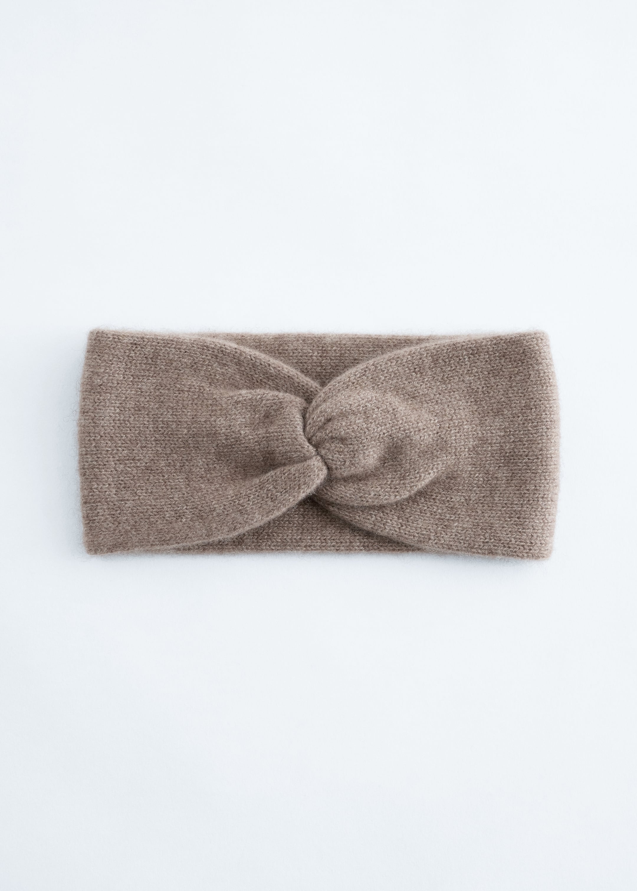 Grösseres Bild ansehen: Ein taupefarbenes Strickstirnband liegt flach in der Vorderansicht, mit einem breiten Design und einem zentralen Twist-Knoten.