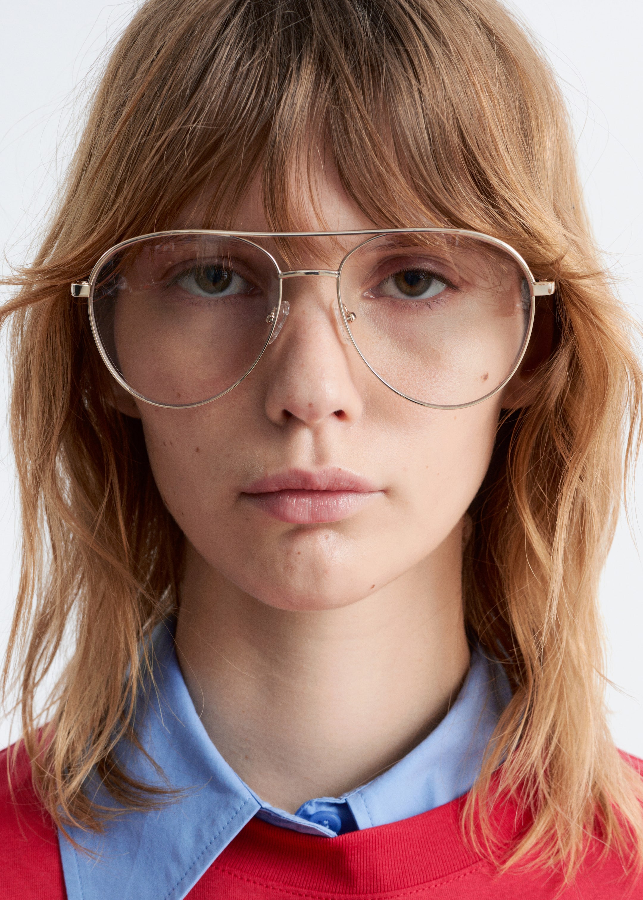 Ver imagen más grande: Las gafas muestran una vista frontal de su delgado armazón de metal en tono dorado al estilo aviador. Están equipadas con lentes transparentes, un puente doble y almohadillas nasales ajustables.