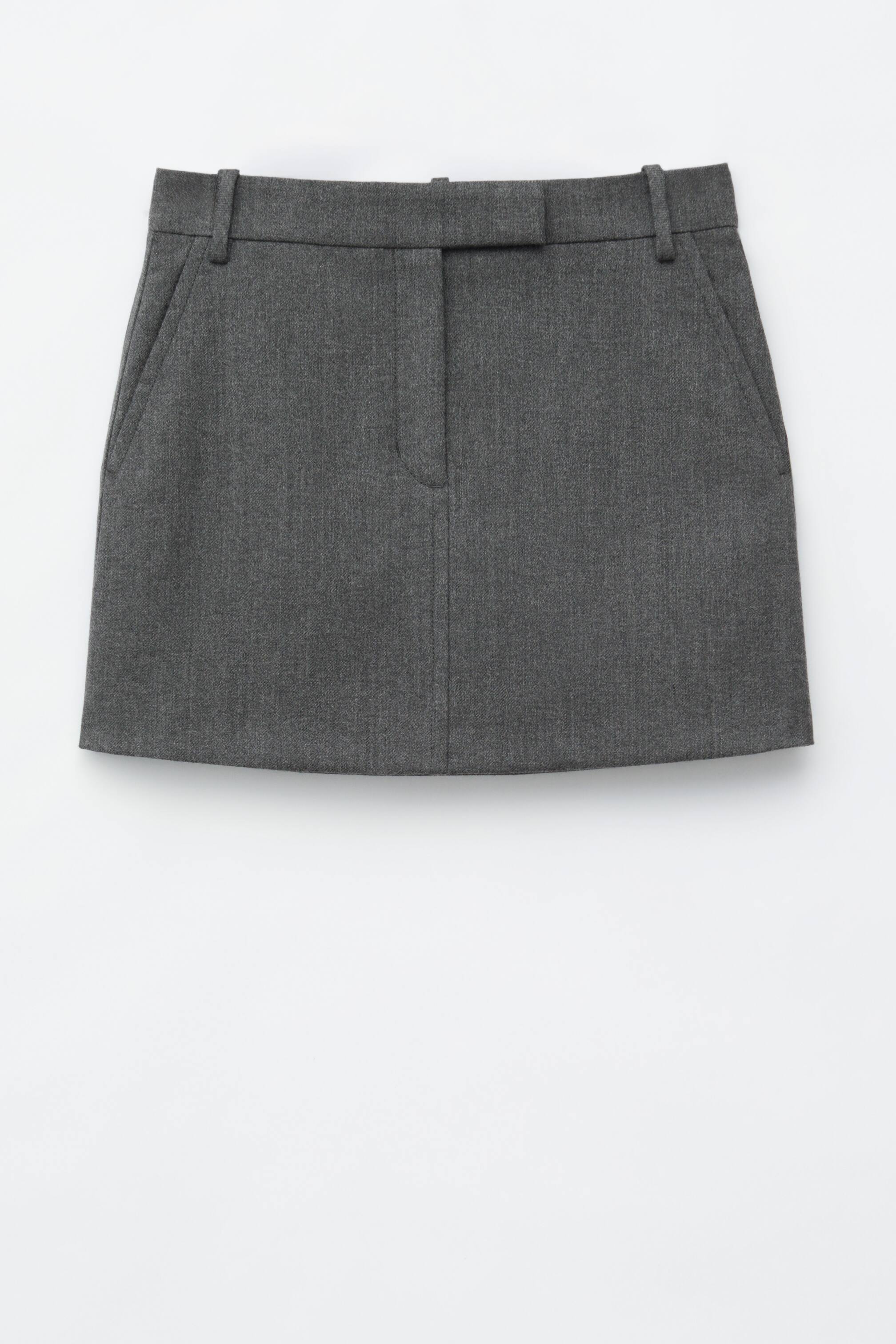 Grösseres Bild ansehen: Ein dunkelgrauer Minirock aus einem Twill-Wollmix wird von vorne präsentiert. Er zeichnet sich durch eine A-Linien-Silhouette, eine reguläre Taille mit Gürtelschlaufen, schräge Seitentaschen und eine zentrale Knopfleiste vorne aus.