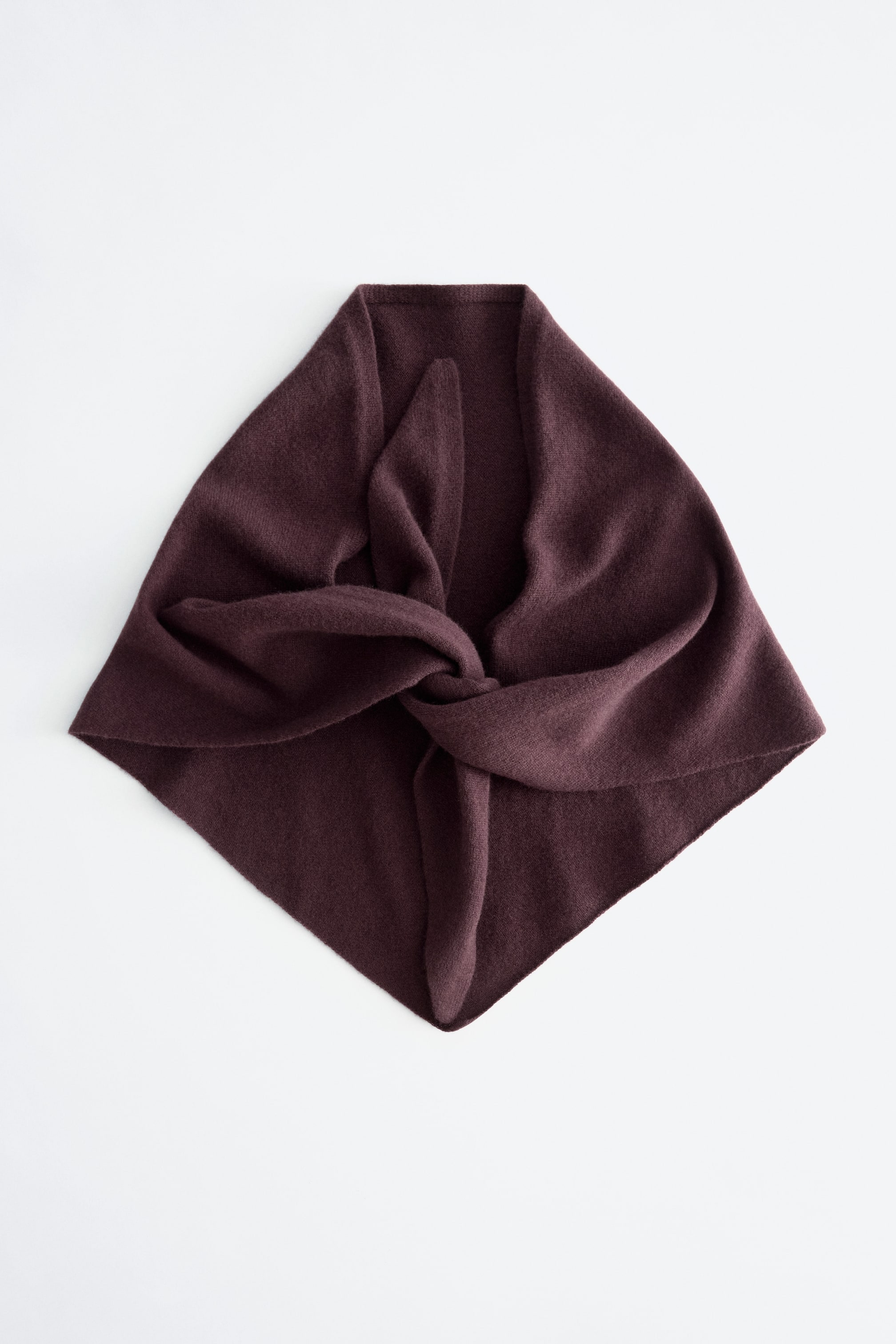 Vis større bilde: Et mykt, mørkt rødbrunt skjerf ligger flatt, brettet og knyttet til en diamantform.