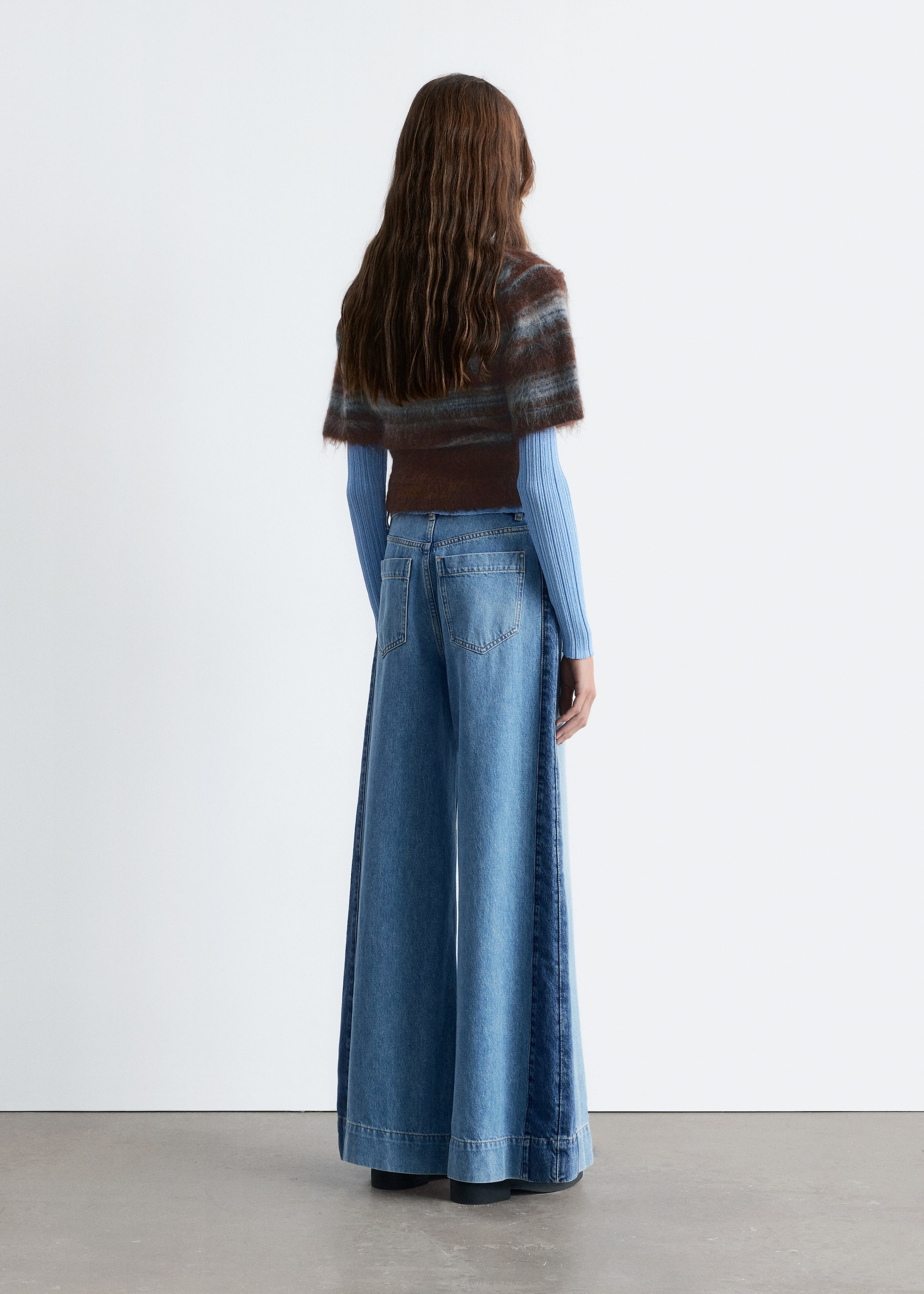 Größeres Bild ansehen: Die High-Waist-Jeans werden von dem Model getragen und präsentieren eine weite, lange Silhouette mit seitlichen Paneeldetails entlang der Beine und einem breiten, abgesteppten Saum.