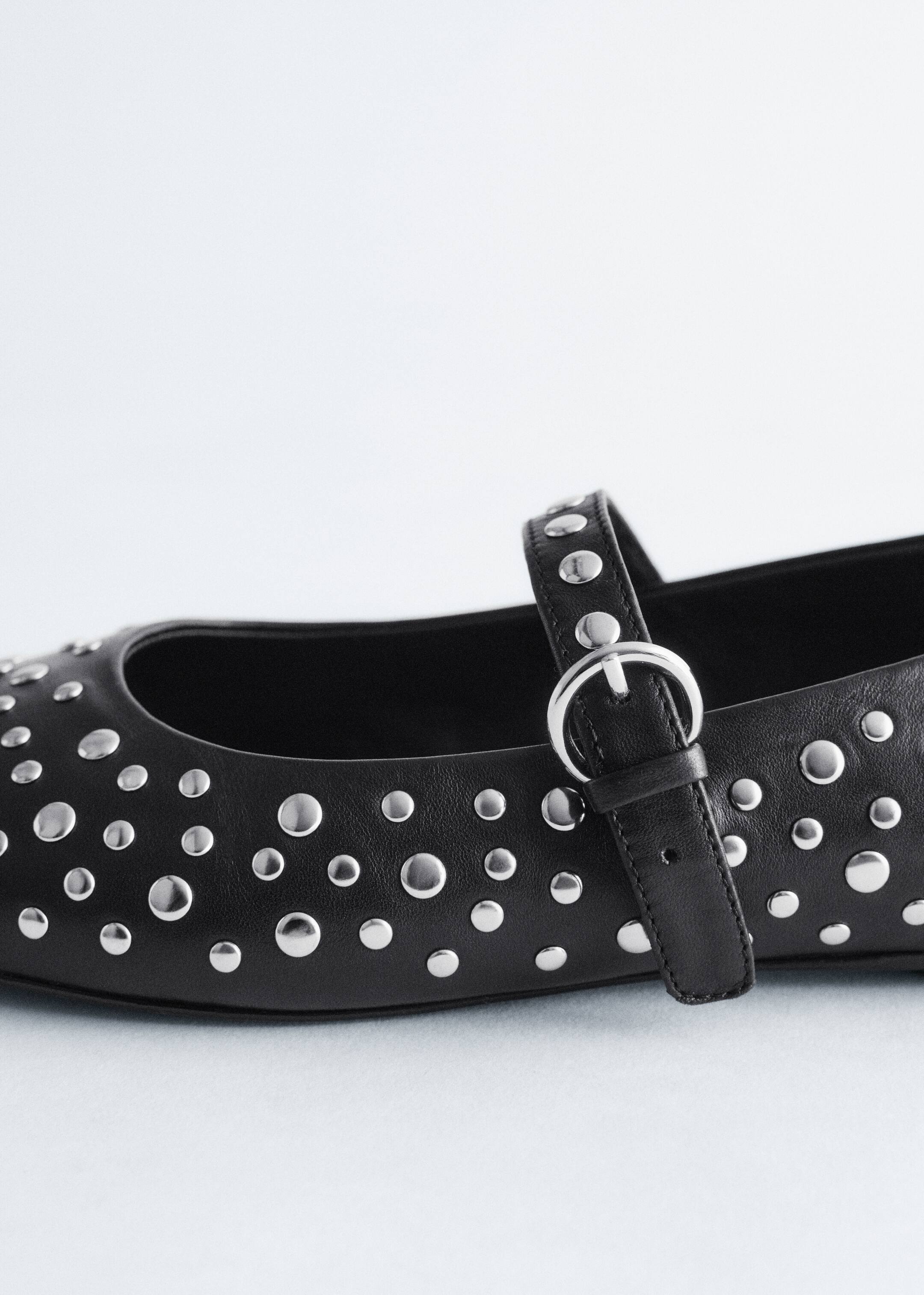 View larger image: A black leather Mary Jane ballet flat is facing right. It is detailed with allover silver-toned metal studs of varying sizes, and a strap featuring a silver-toned buckle is crossing the top of the foot.