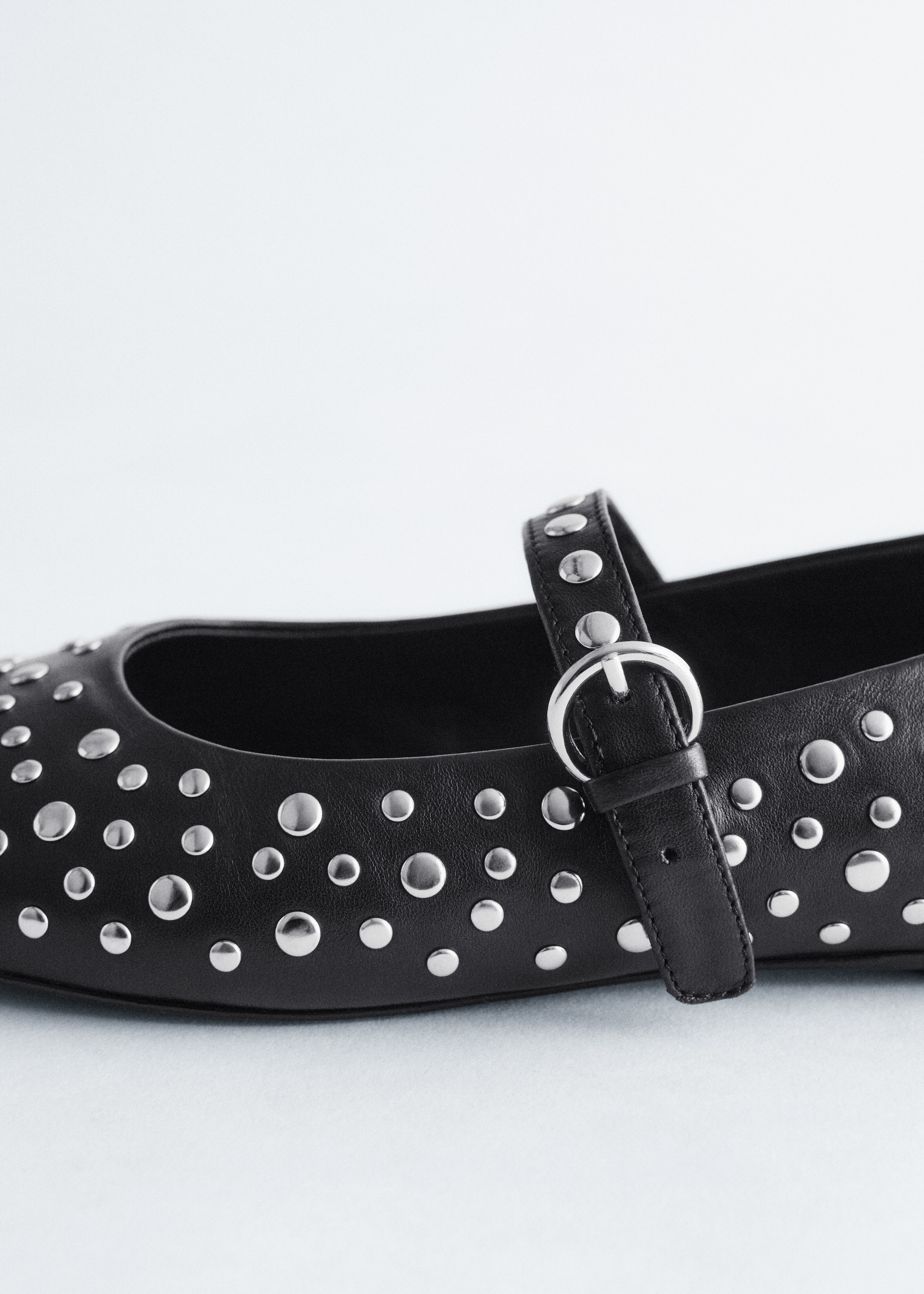 View larger image: A black leather Mary Jane ballet flat is facing right. It is detailed with allover silver-toned metal studs of varying sizes, and a strap featuring a silver-toned buckle is crossing the top of the foot.