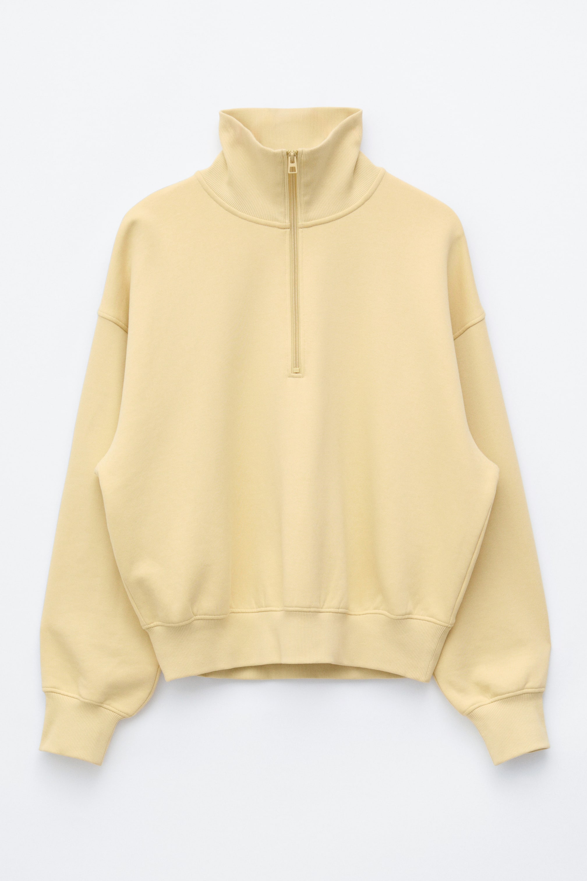 Ver imagen más grande: Se muestra una sudadera de media cremallera en amarillo claro, vista de frente, con un corte holgado, cuello alto acanalado con cremallera a juego, hombros caídos y puños y bajo acanalados.