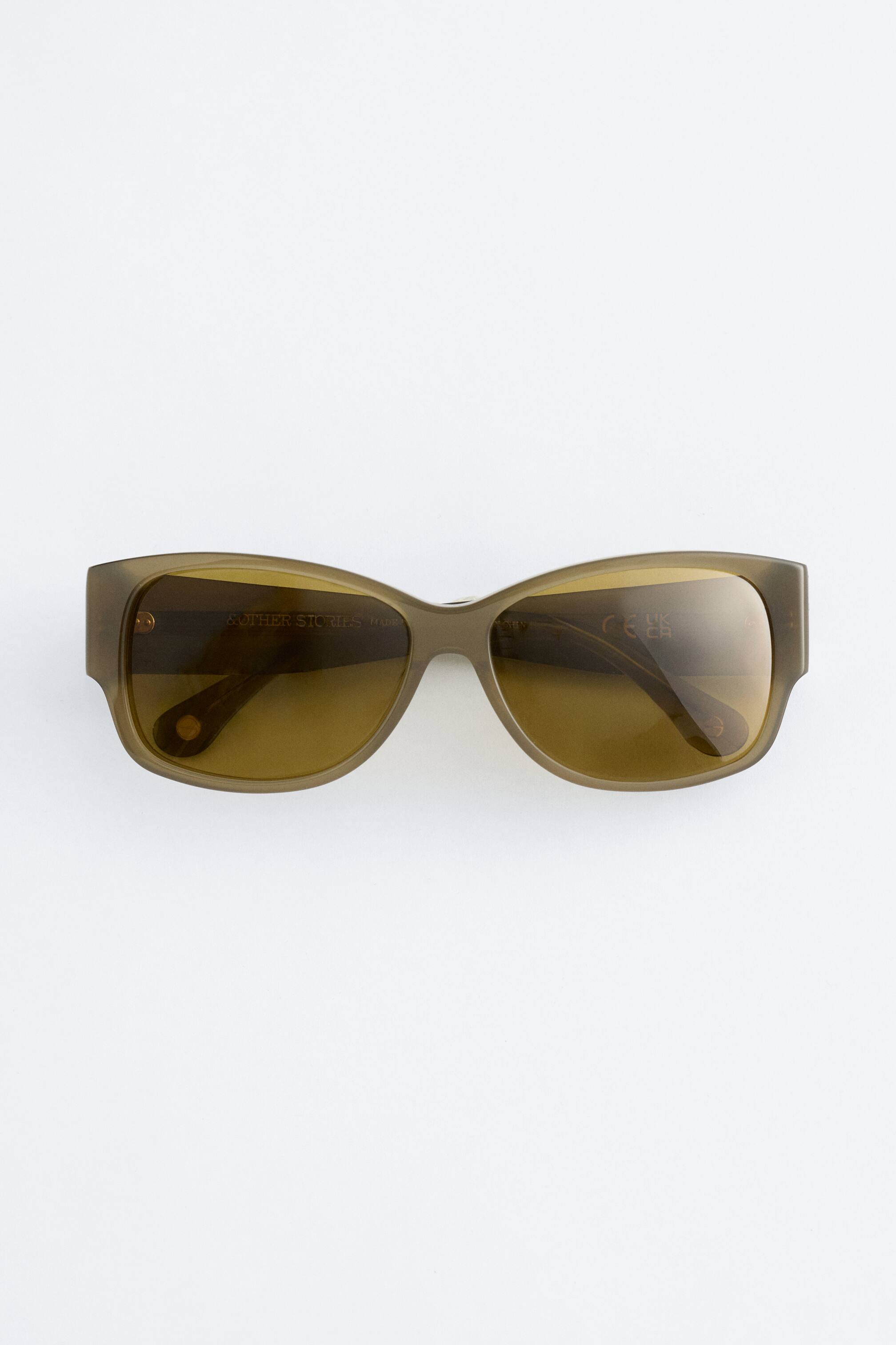 Visualizza immagine più grande: Occhiali da sole in acetato verde oliva con montatura ovale dai bordi arrotondati e aste larghe, presentati frontalmente. Lenti sfumate in tonalità sono visibili.