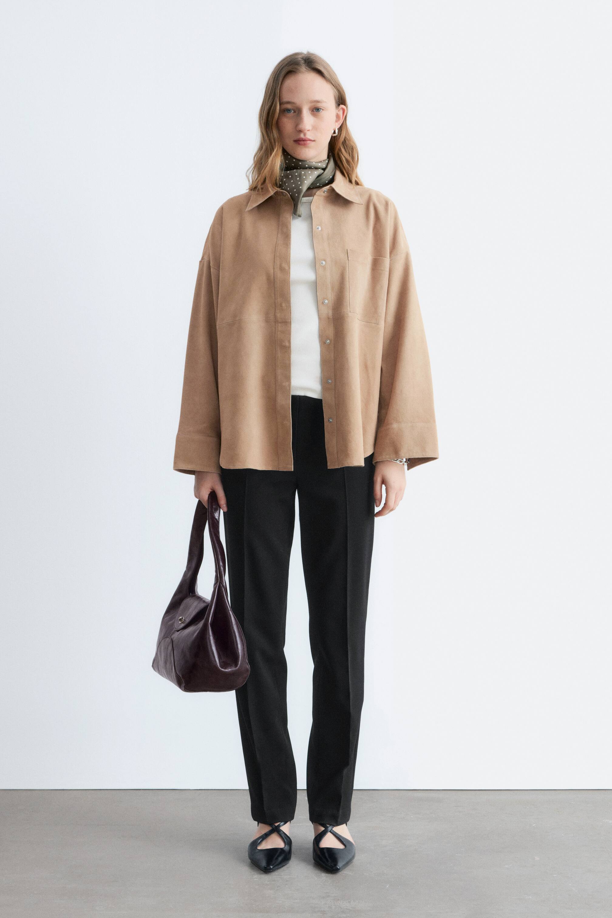 Agrandir l'image: Le mannequin porte un pantalon noir à coupe régulière avec des jambes droites et des plis marqués.