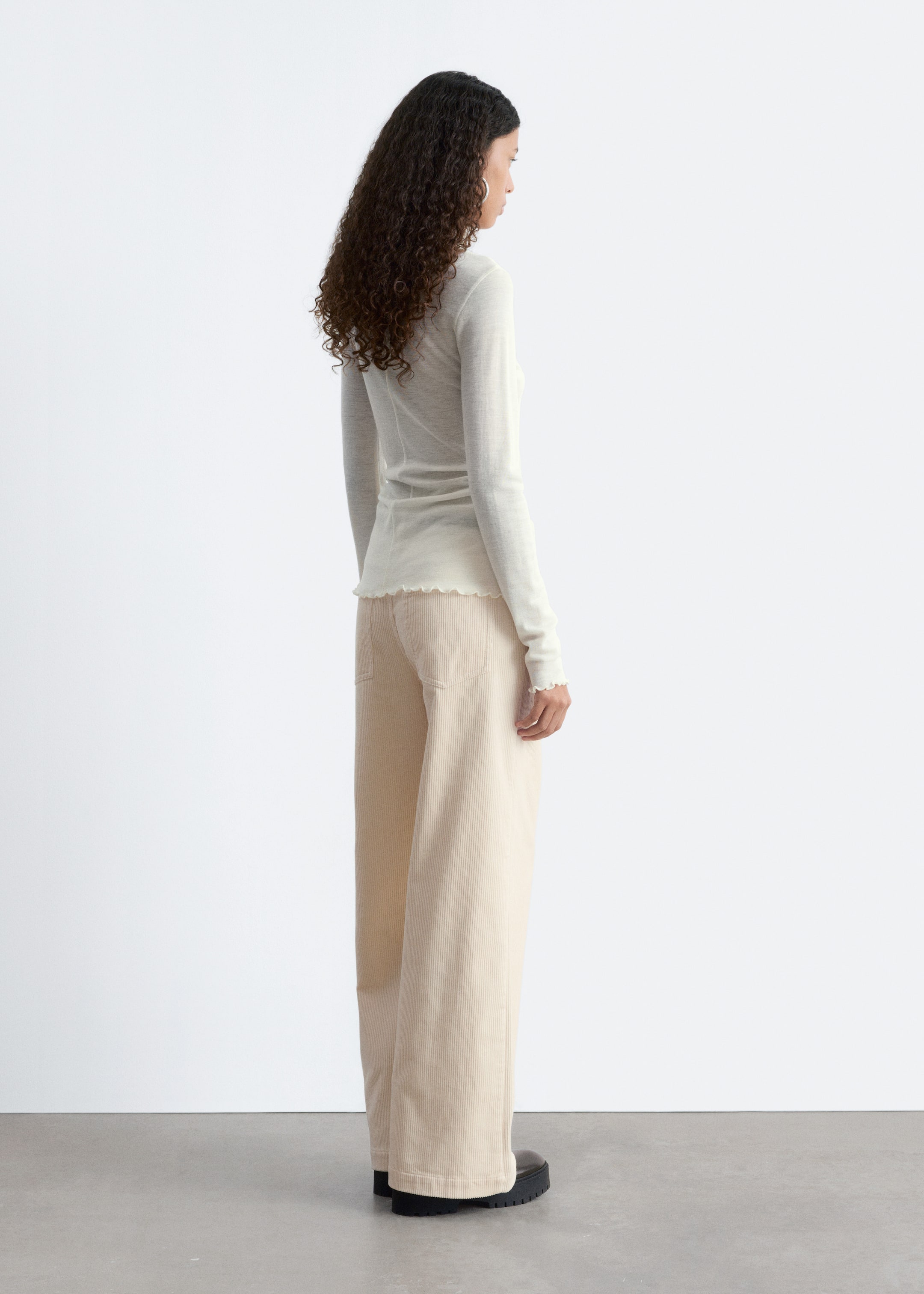 Grotere afbeelding bekijken: Een gebroken wit, lang mouwenshirt met gegolfde boorden en zoom wordt gedragen met beige corduroy broek met wijde pijpen, voorzien van achterzakken, bekeken vanuit een hoek rechtsachter.
