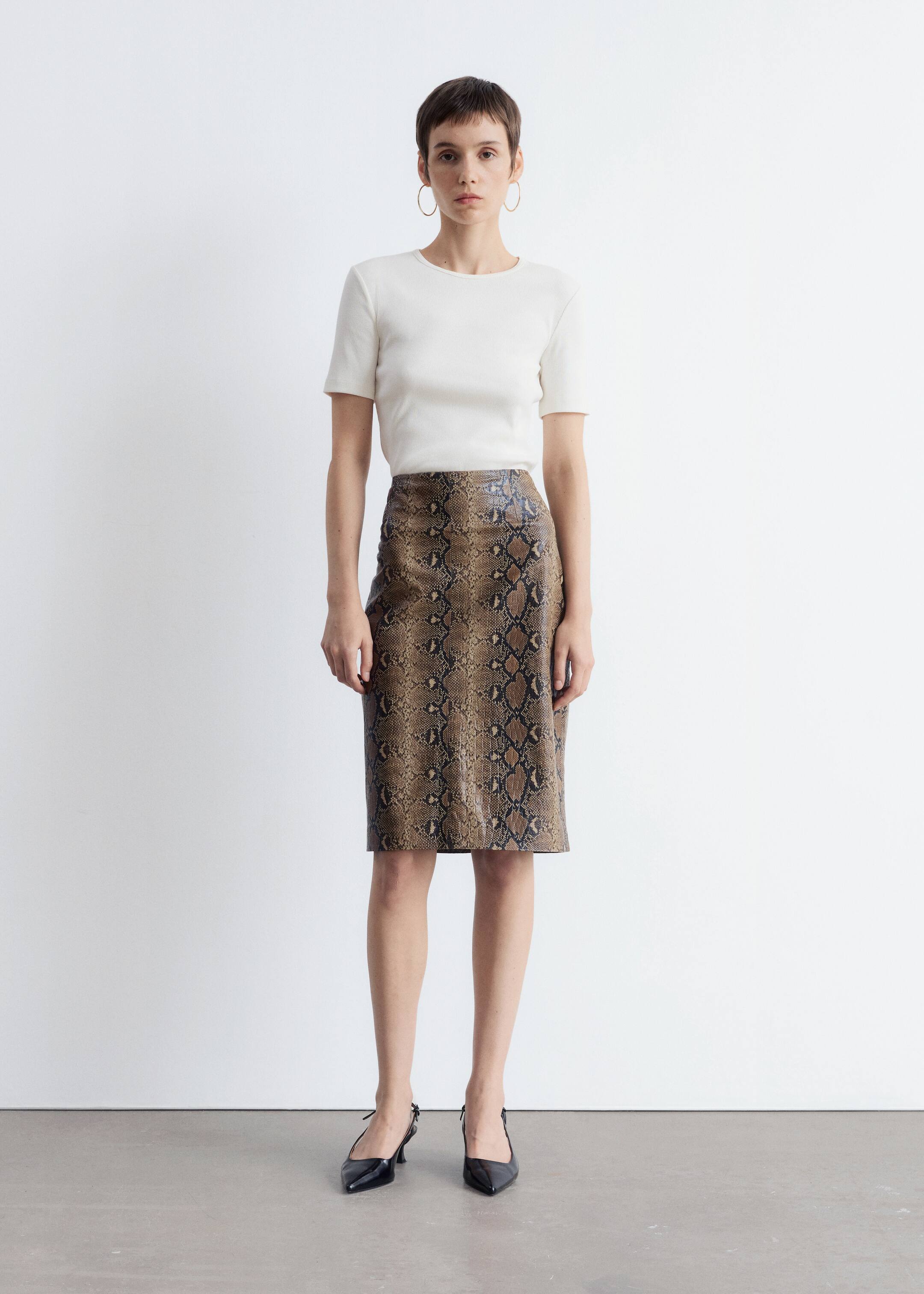 Agrandir l'image: Un haut blanc cassé à manches courtes et col rond est porté, rentré dans une jupe crayon taille haute et longueur genou. La jupe en faux cuir présente un imprimé serpent marron et noir avec un éclat subtil, et la tenue est présentée de face.
