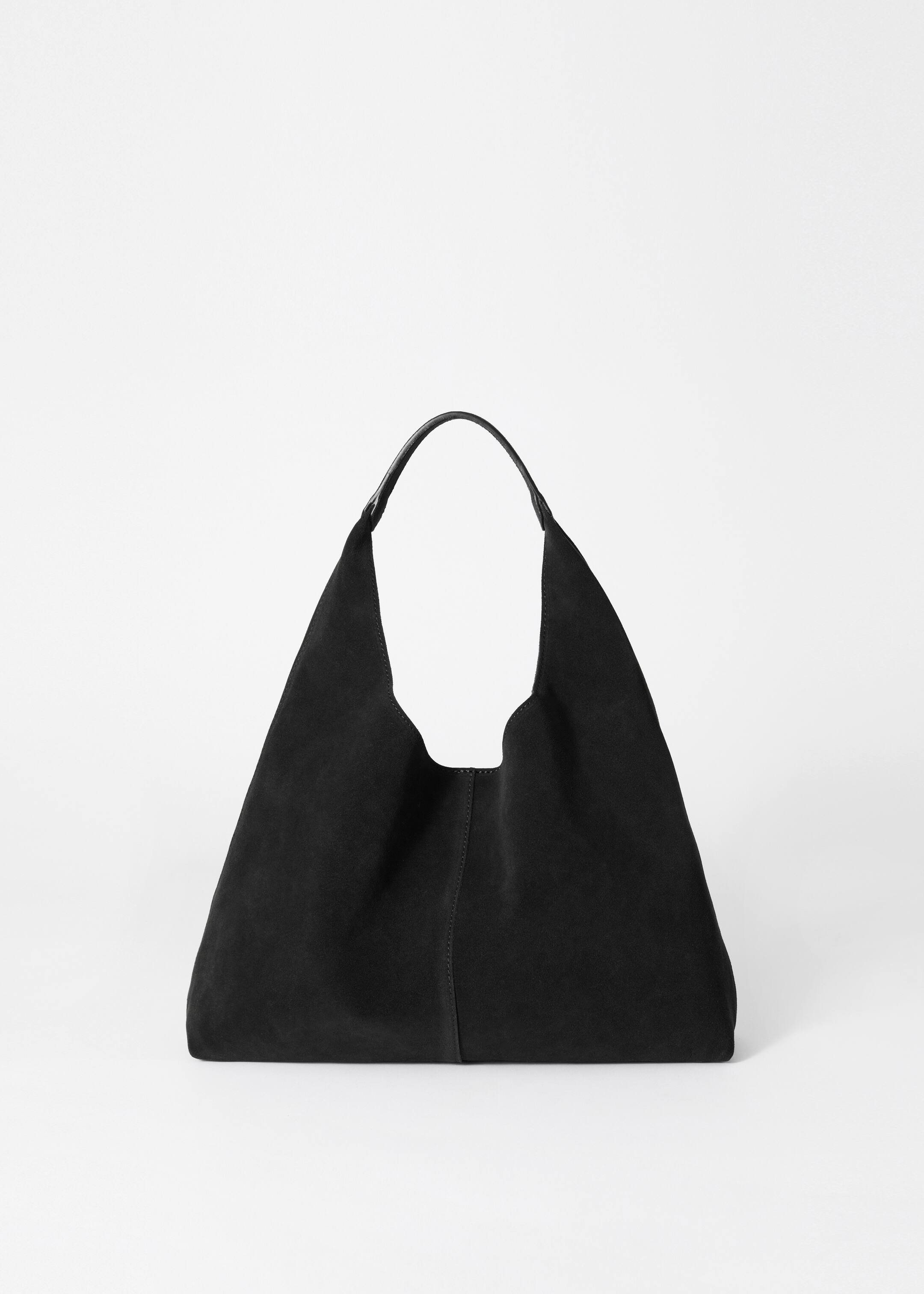 View larger image: A black tote bag is appearing from the front, crafted from smooth suede with a matte finish. A decorative vertical seam is running down the center of the bag, and a single curved handle is extending from the top.