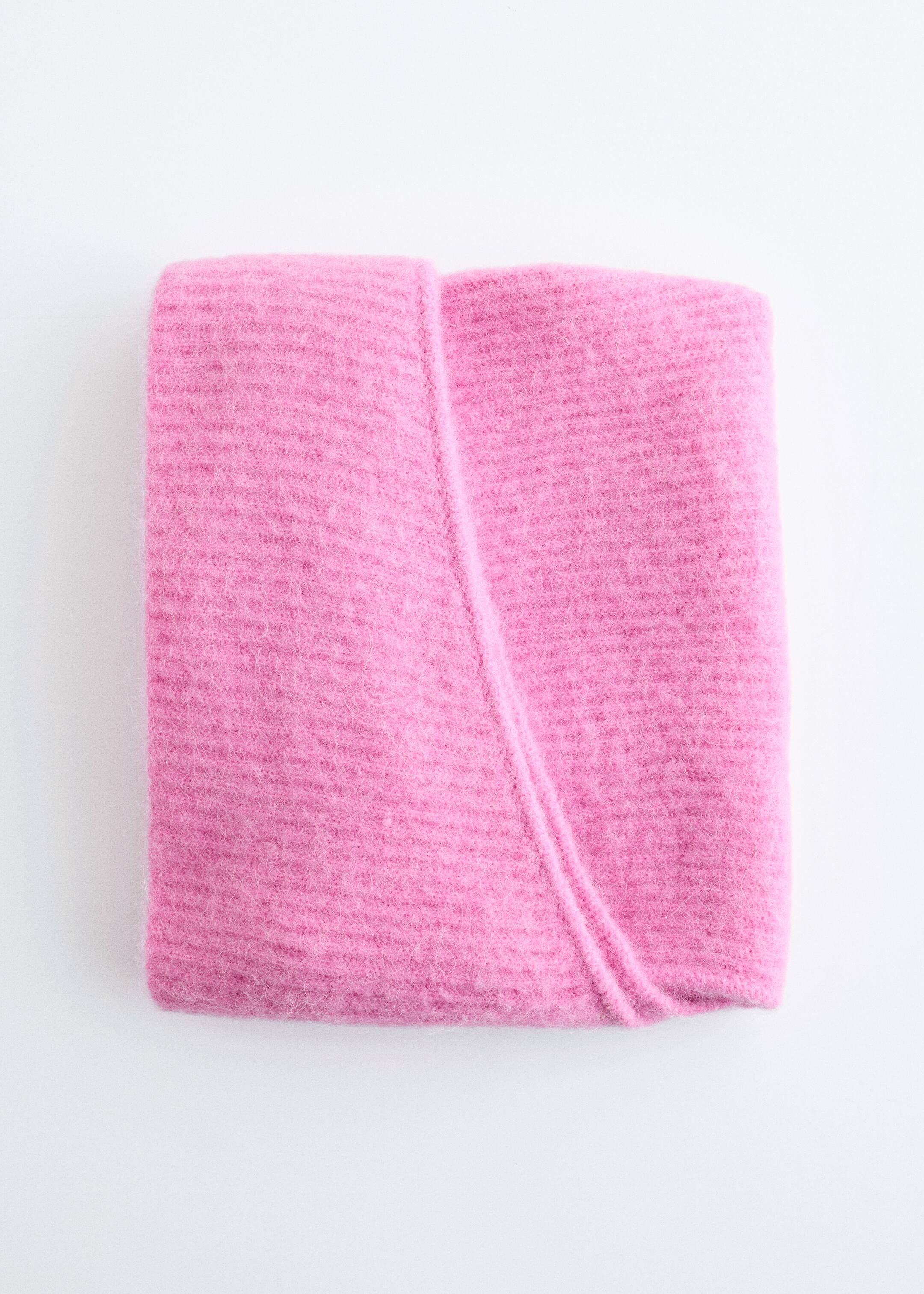 Visa större bild: En rosa tröja visar en fluffig, borstad textur med subtila horisontella stickade linjer, snyggt vikt i en rektangulär form med ett tydligt diagonalt veck över dess övre yta.