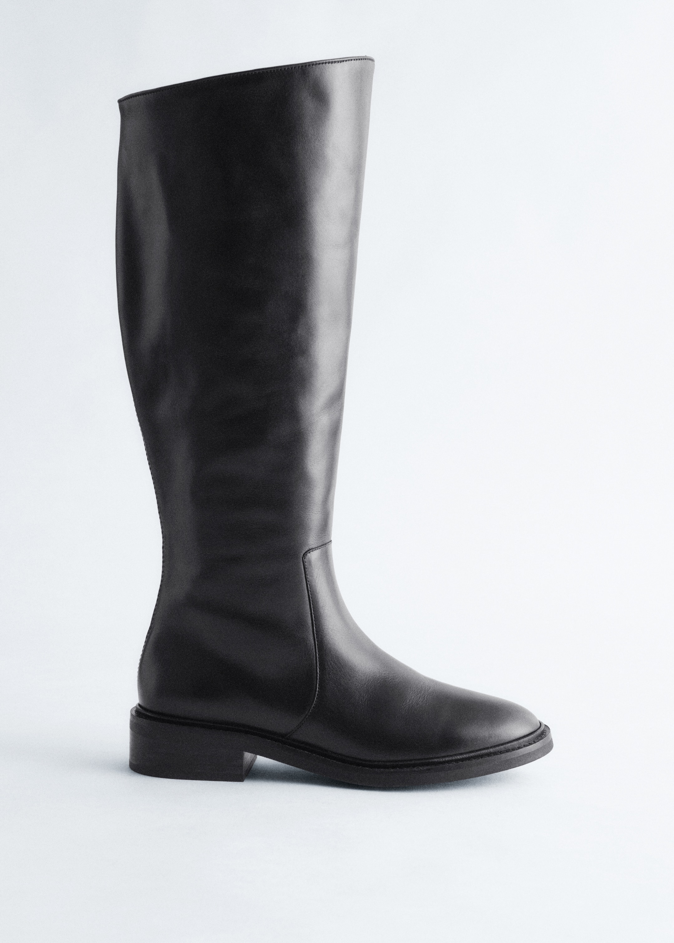 Größeres Bild anzeigen: Ein schwarzer hoher Stiefel steht, nach links geneigt. Er verfügt über ein glattes Lederobermaterial, eine abgerundete Spitze und einen niedrigen Blockabsatz.