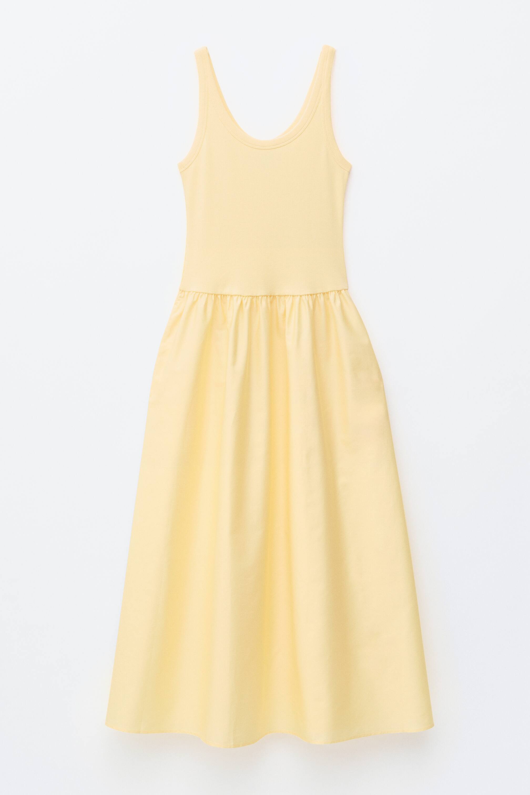 Visa större bild: En ljusgul tankklänning visas framifrån, med en ribbad överdel med rund hals och breda axelband som övergår i en rynkad A-linjeformad kjol, vilket skapar en lång, flytande silhuett.