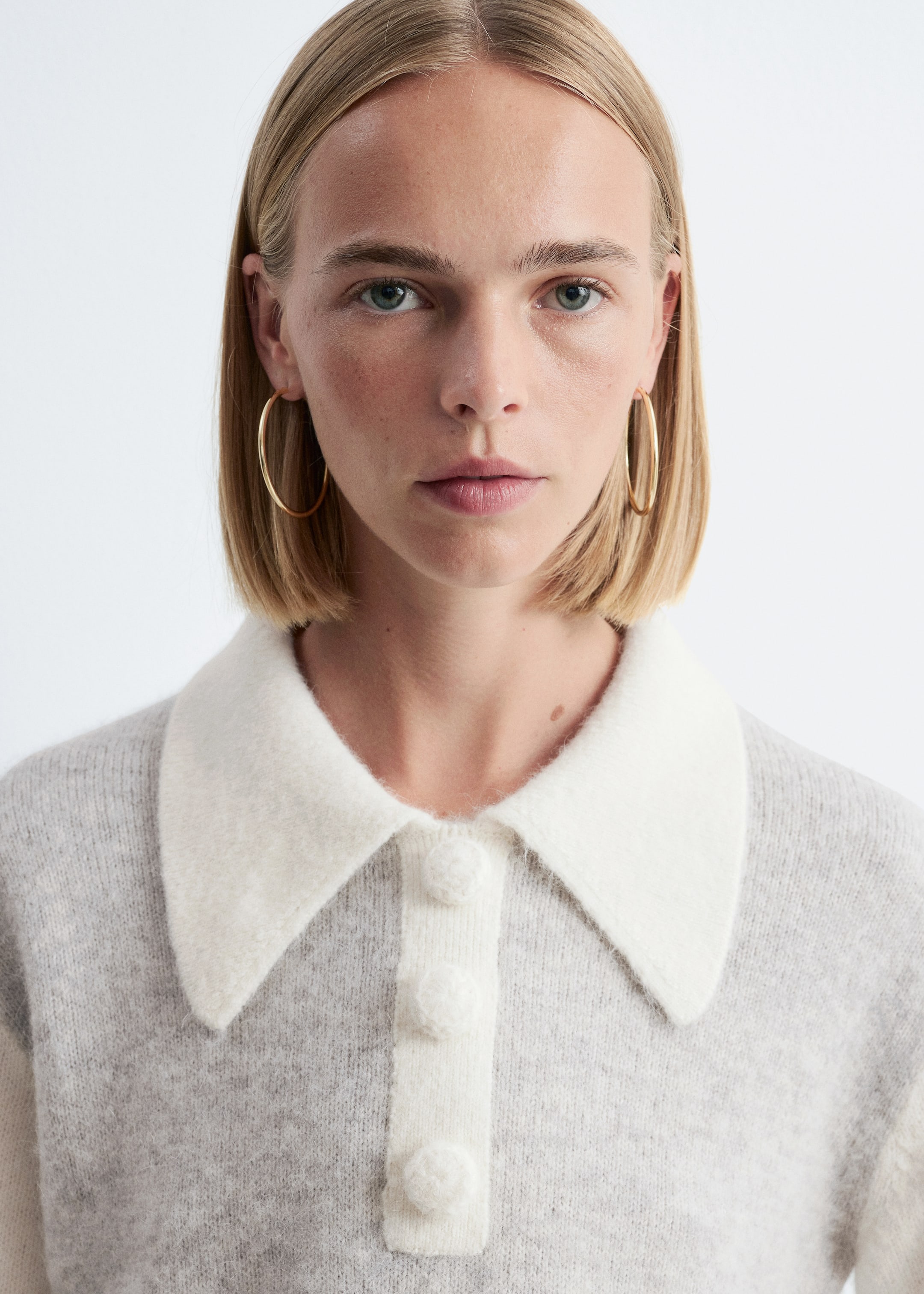 Ver imagen más grande: La modelo lleva un jersey de punto gris claro con un cuello blanco extragrande y una tapeta decorativa blanca con tres grandes botones cubiertos.