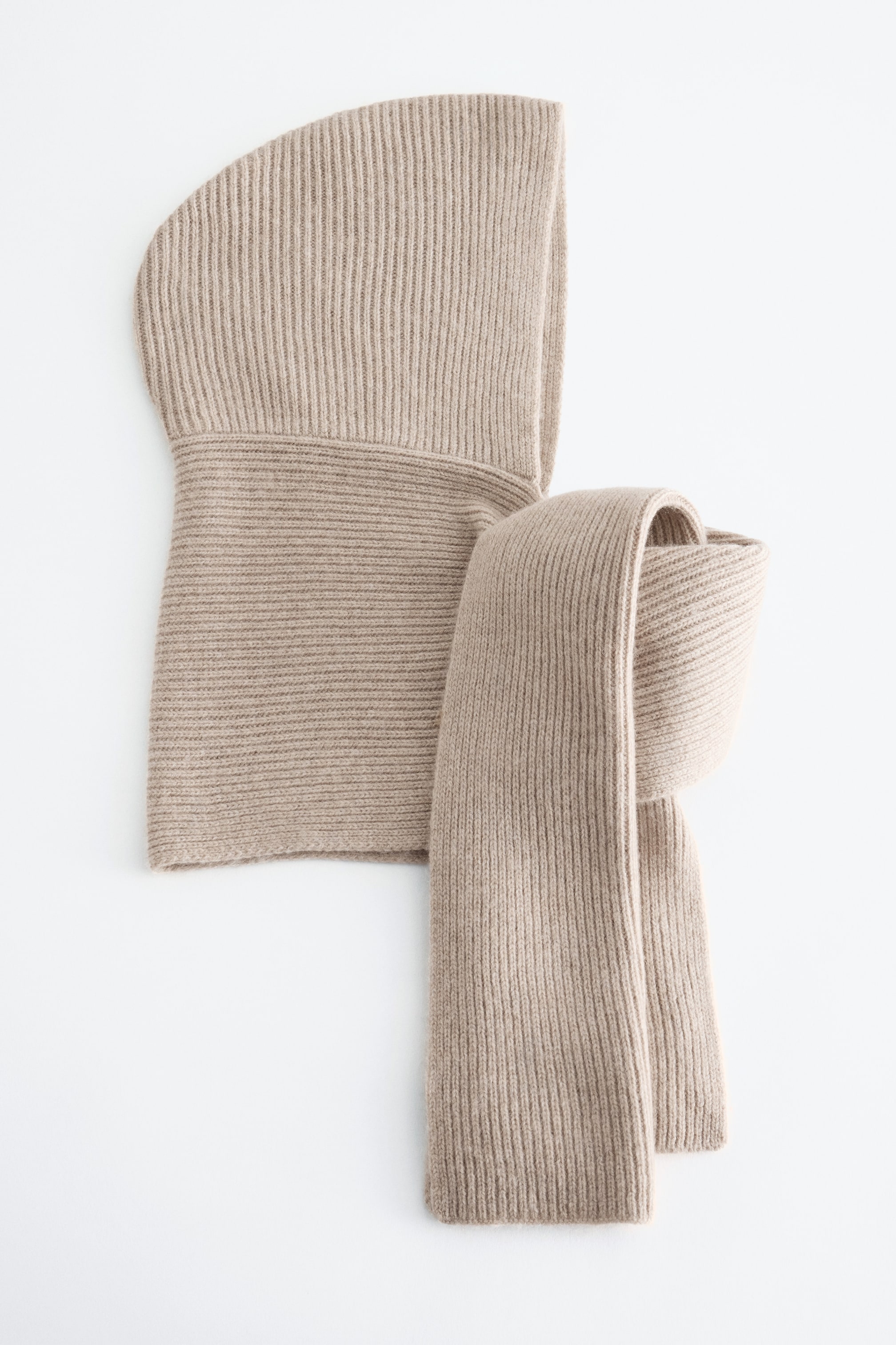 Vezi imaginea mai mare: O eșarfă cu glugă din tricot cu model rib este așezată întins. Gluga sa generoasă stă dreaptă, iar partea de eșarfă este înfășurată o dată în jurul bazei, cu un capăt coborând în jos.