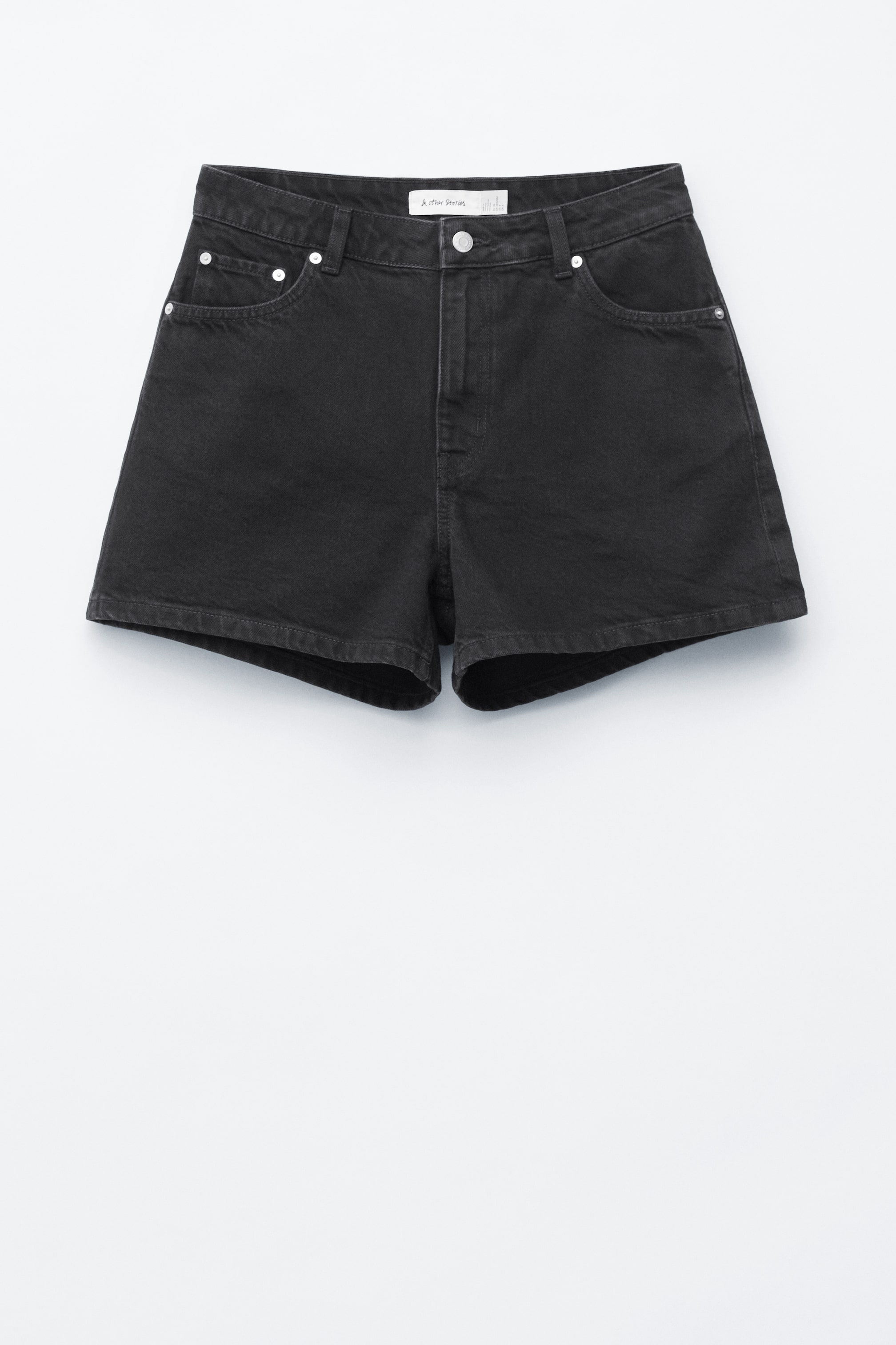 Grotere afbeelding bekijken: Zwarte denim shorts worden van de voorkant gepresenteerd en tonen een losse pasvorm. Ze zijn voorzien van een rits- en knoopsluiting, twee voorzakken, een muntzakje en zilveren klinknagels.