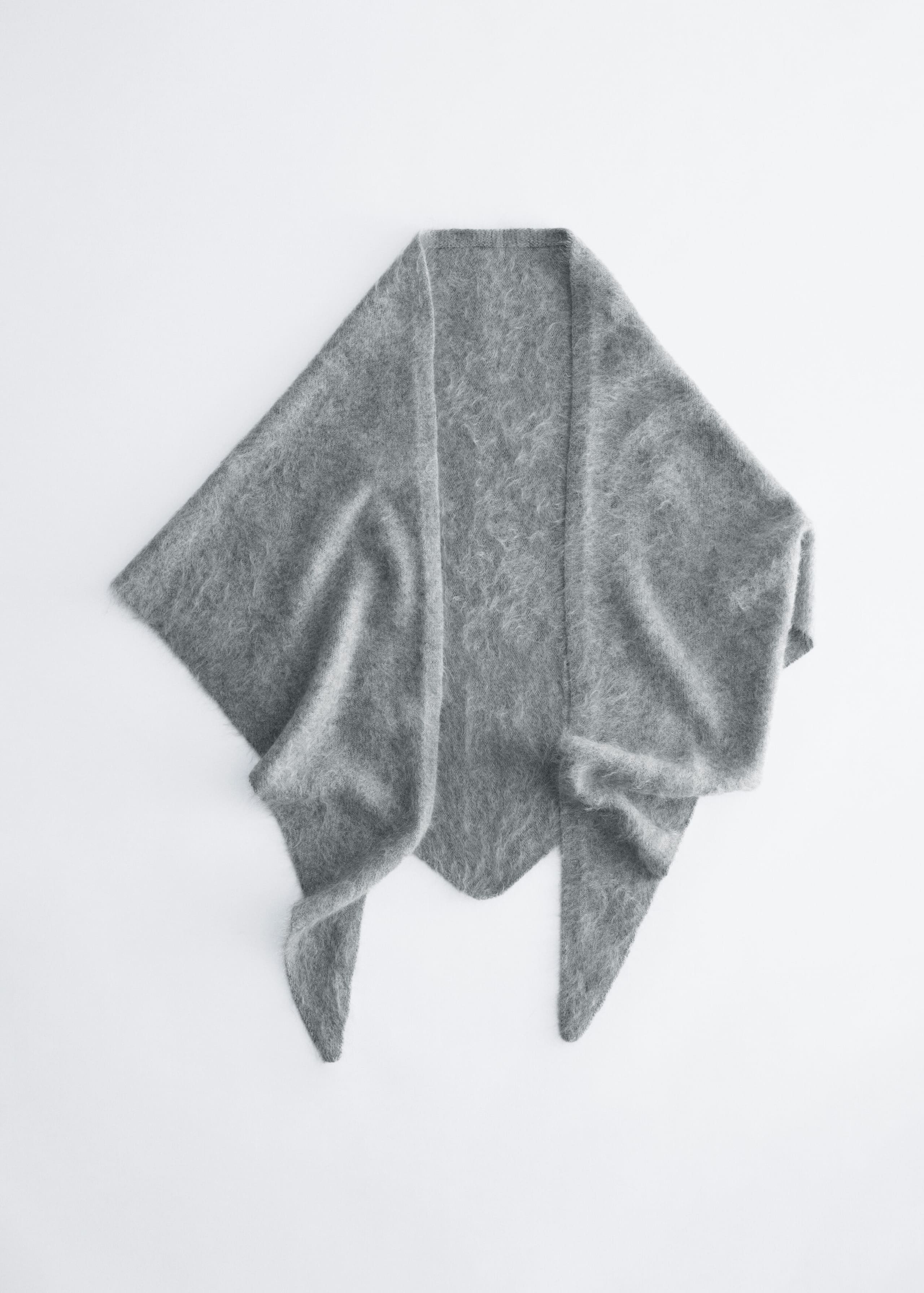 A gray knit shawl is shown from the front, featuring a fuzzy, brushed texture and a triangular silhouette. The shawl is draped to show two pointed ends hanging down in the front and a pointed center back panel.