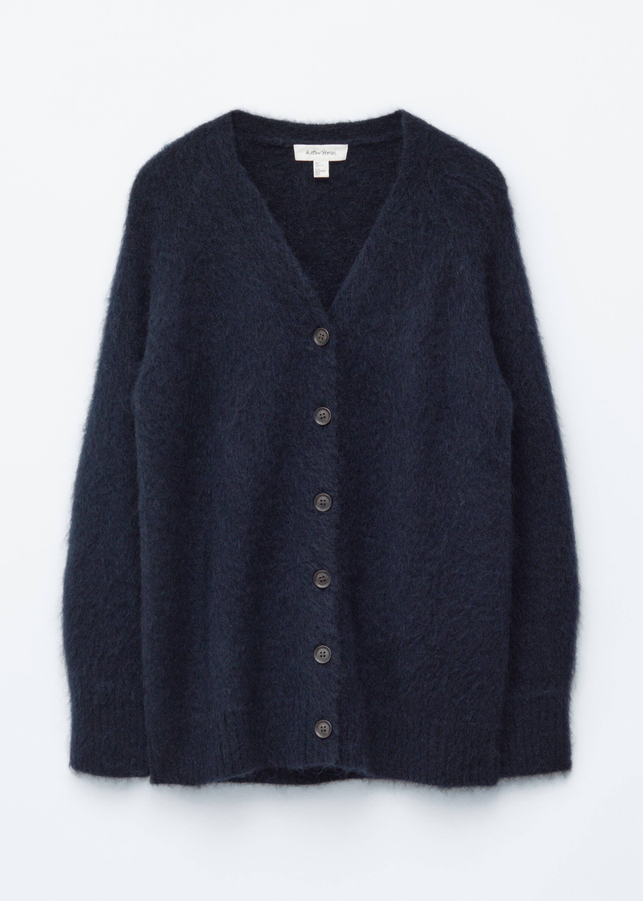 Visualizza immagine più grande: Un cardigan lavorato a maglia blu scuro e soffice è presentato frontalmente, con uno scollo a V e sei bottoni circolari scuri lungo il centro anteriore.