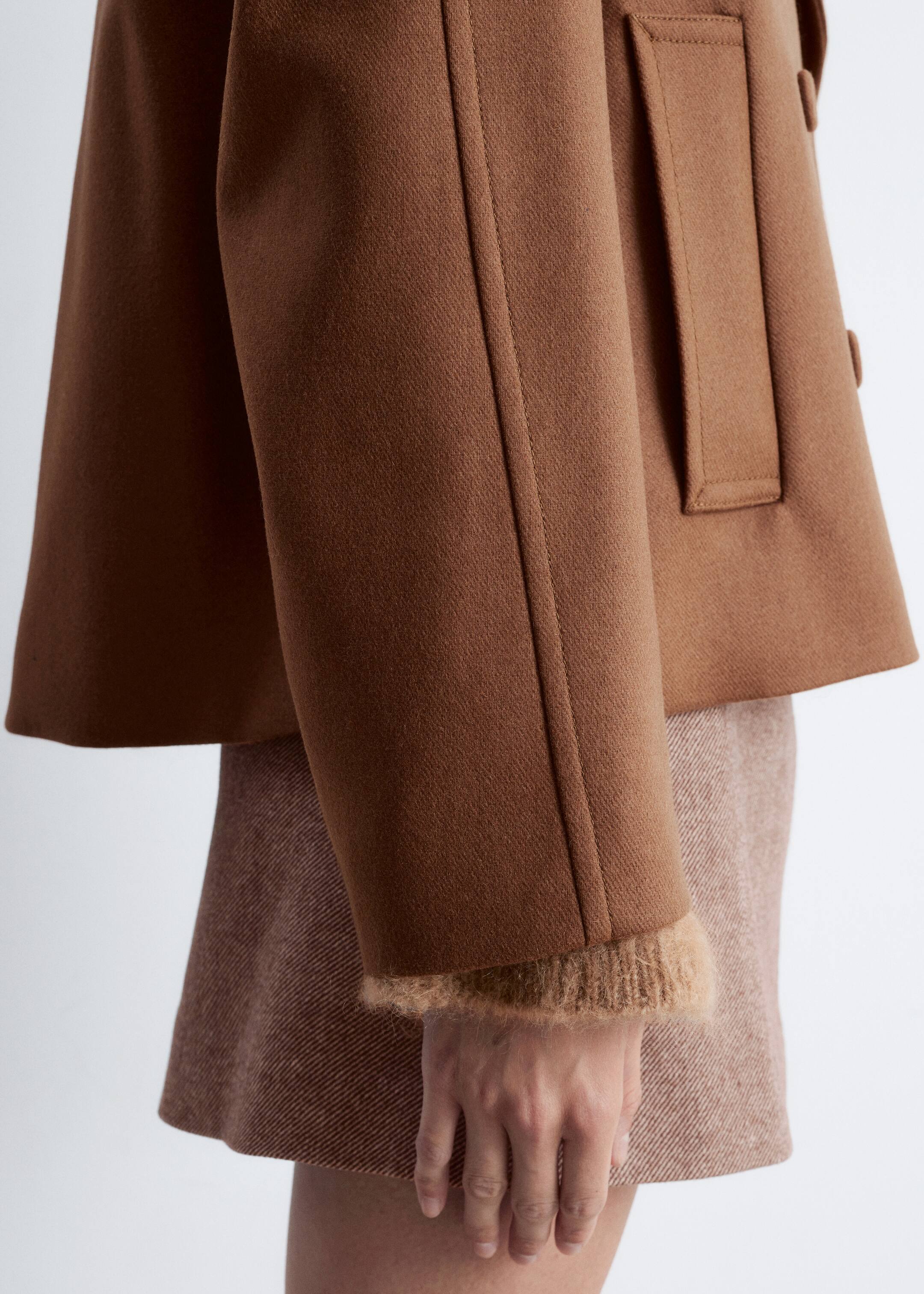 Agrandir l'image: Une veste marron en mélange de laine est portée par un mannequin, avec une silhouette trapèze courte, une grande poche à rabat rectangulaire et des poignets duveteux de couleur marron plus clair. La veste est superposée à une jupe texturée de couleur marron plus clair.