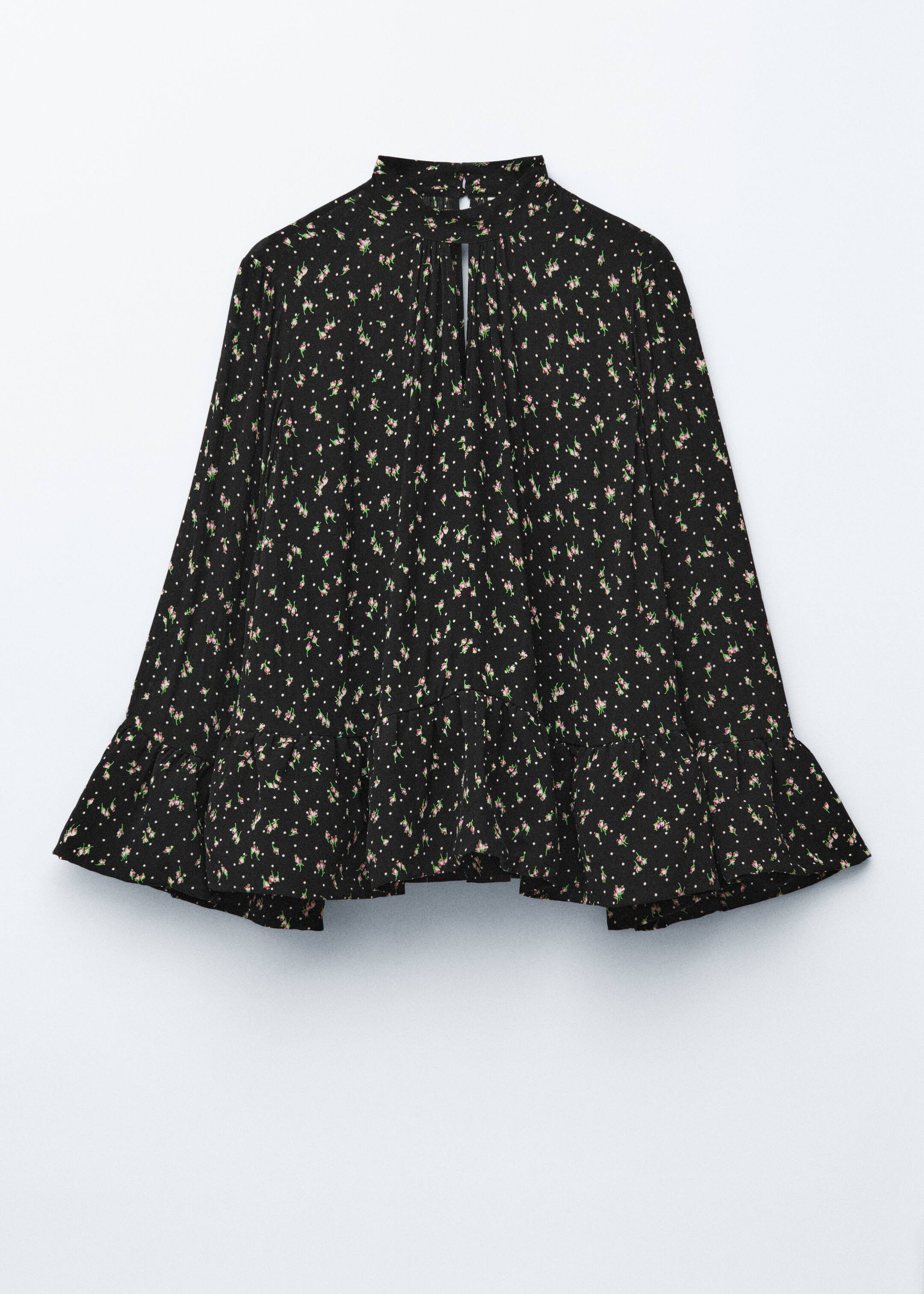 Ver imagem maior: A blusa preta, com padrão de pequenas flores cor-de-rosa e bolinhas brancas, está a ser apresentada de frente. Apresenta uma silhueta larga e solta, uma gola alta com fecho de botão tipo casa de chave, um decote recortado em forma de V, e detalhes franzidos na bainha inferior e nas mangas largas.