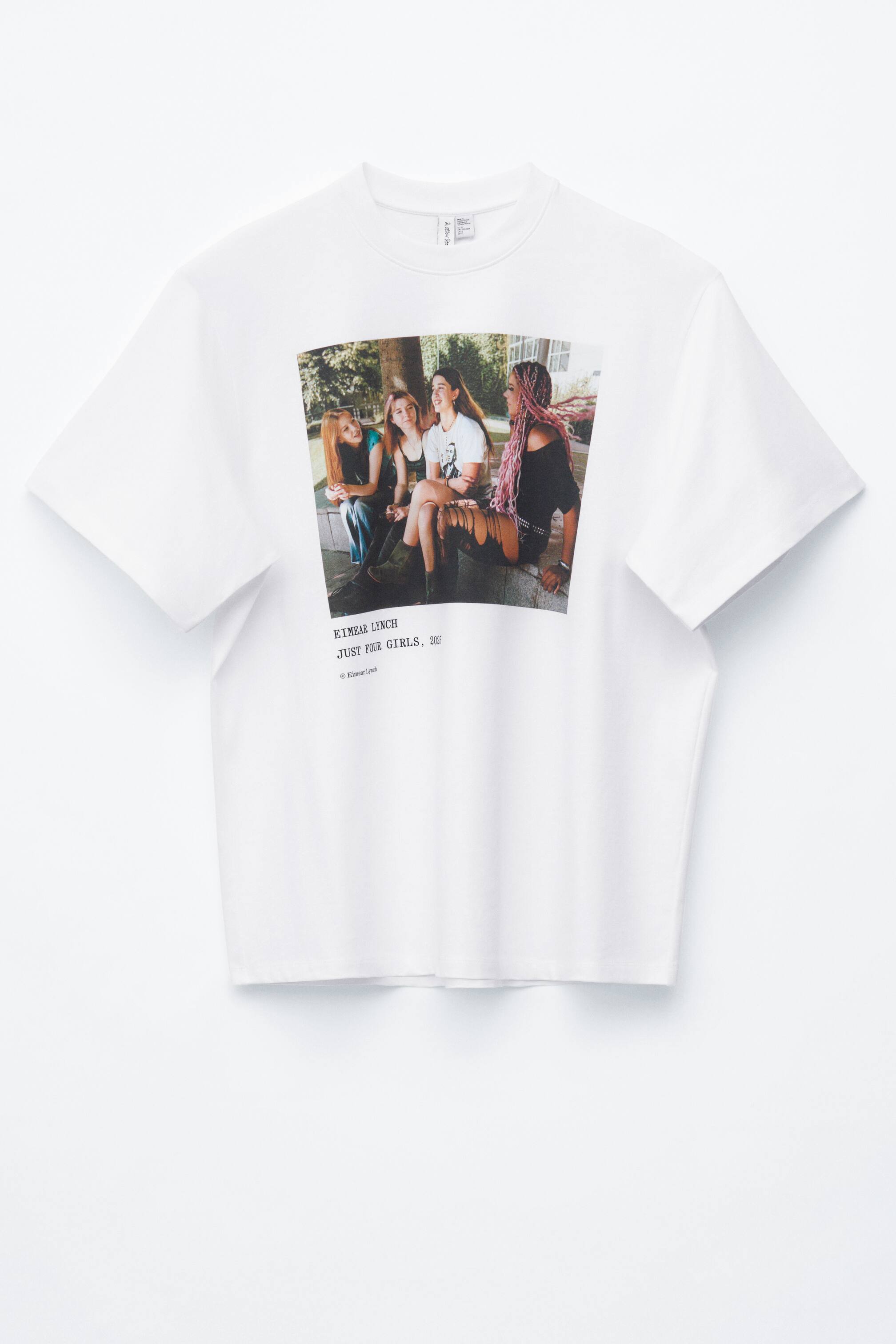Näytä suurempi kuva: Valkoinen, eteenpäin suuntautuva t-paita esittelee suuren, suorakulmaisen valokuvapainatuksen rinnassaan, jossa neljä nuorta naista istuu ja nauraa. Teksti "EIMEAR LYNCH", "JUST FOUR GIRLS, 2015" ja "© Eimear Lynch" on painettu alle. T-paita on suunniteltu ylisuurena, siinä on lyhyet hihat ja pyöreä pääntie.