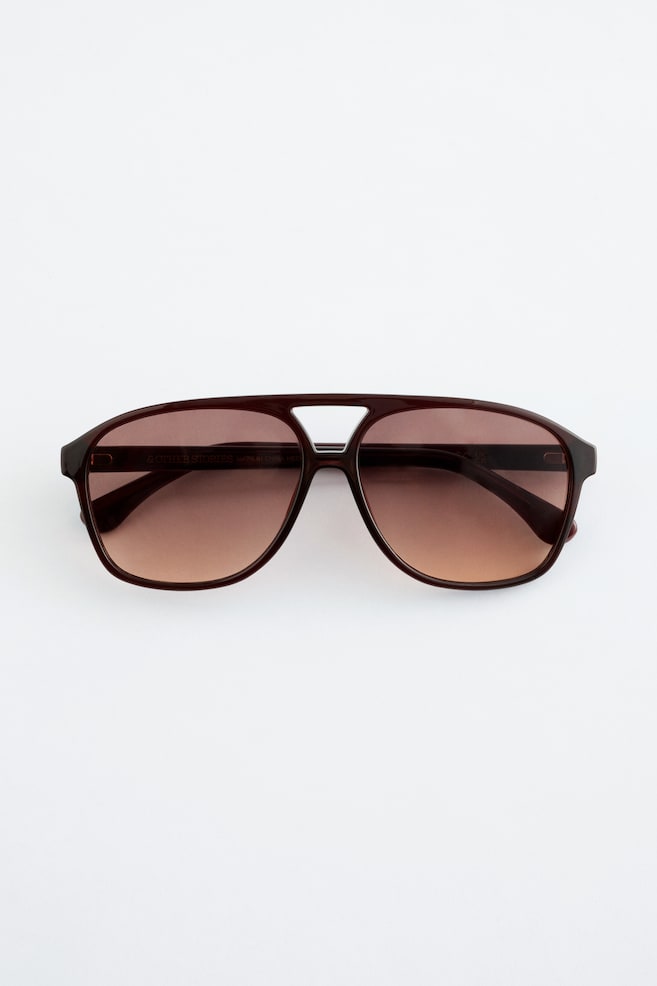 Ein Paar dunkelbraune Aviator-Sonnenbrillen wird von vorne präsentiert, mit braunen Verlaufsgläsern und einem Doppelsteg. - 1
