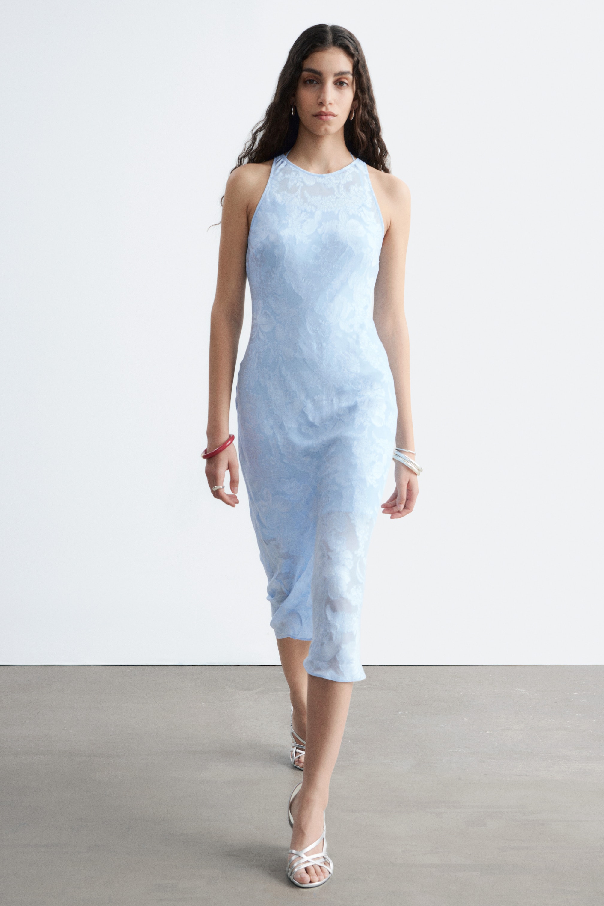 Agrandir l'image: Une robe midi sans manches bleu clair, avec un col rond et un motif texturé, est portée par le mannequin. Une robe nuisette de ton plus clair est visible en dessous, offrant une couverture.
