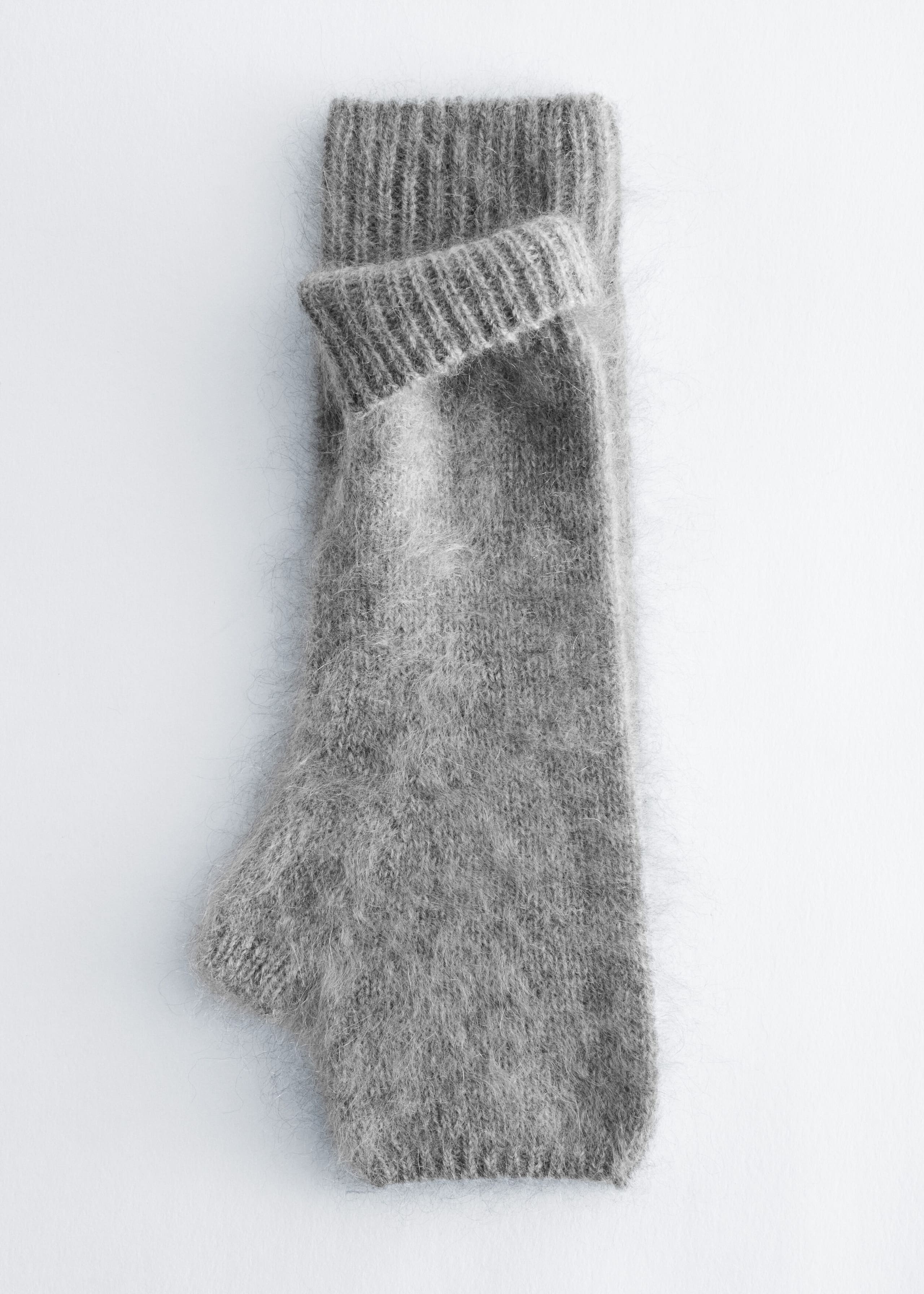 A pair of gray, brushed-finish fingerless gloves lies flat, with one glove folded over the other to showcase the ribbed cuffs and fuzzy, textured knit.
