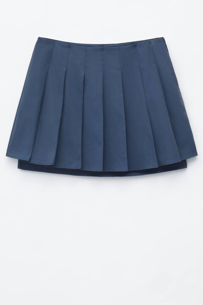 Una falda plisada azul oscuro presenta su parte frontal, con numerosos pliegues verticales y definidos que se extienden desde una cintura plana. El dobladillo de la falda muestra un sutil efecto de capas. - 1
