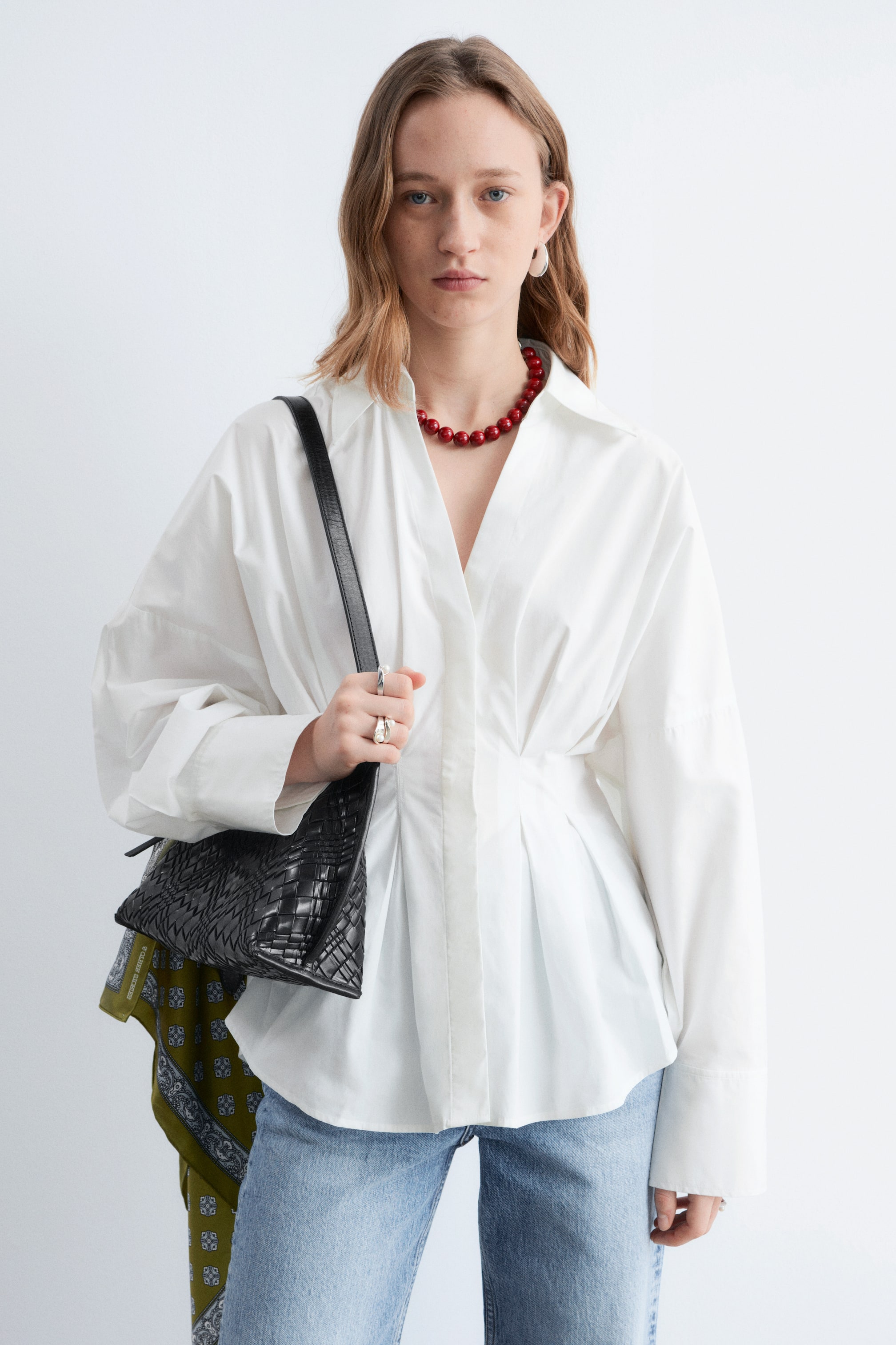 Преглед на по-голямо изображение: Бяла риза с разширена яка и дълги ръкави с широки маншети. Дизайнът е с вталена талия и вертикални плисета, които се разширяват към подгъва.