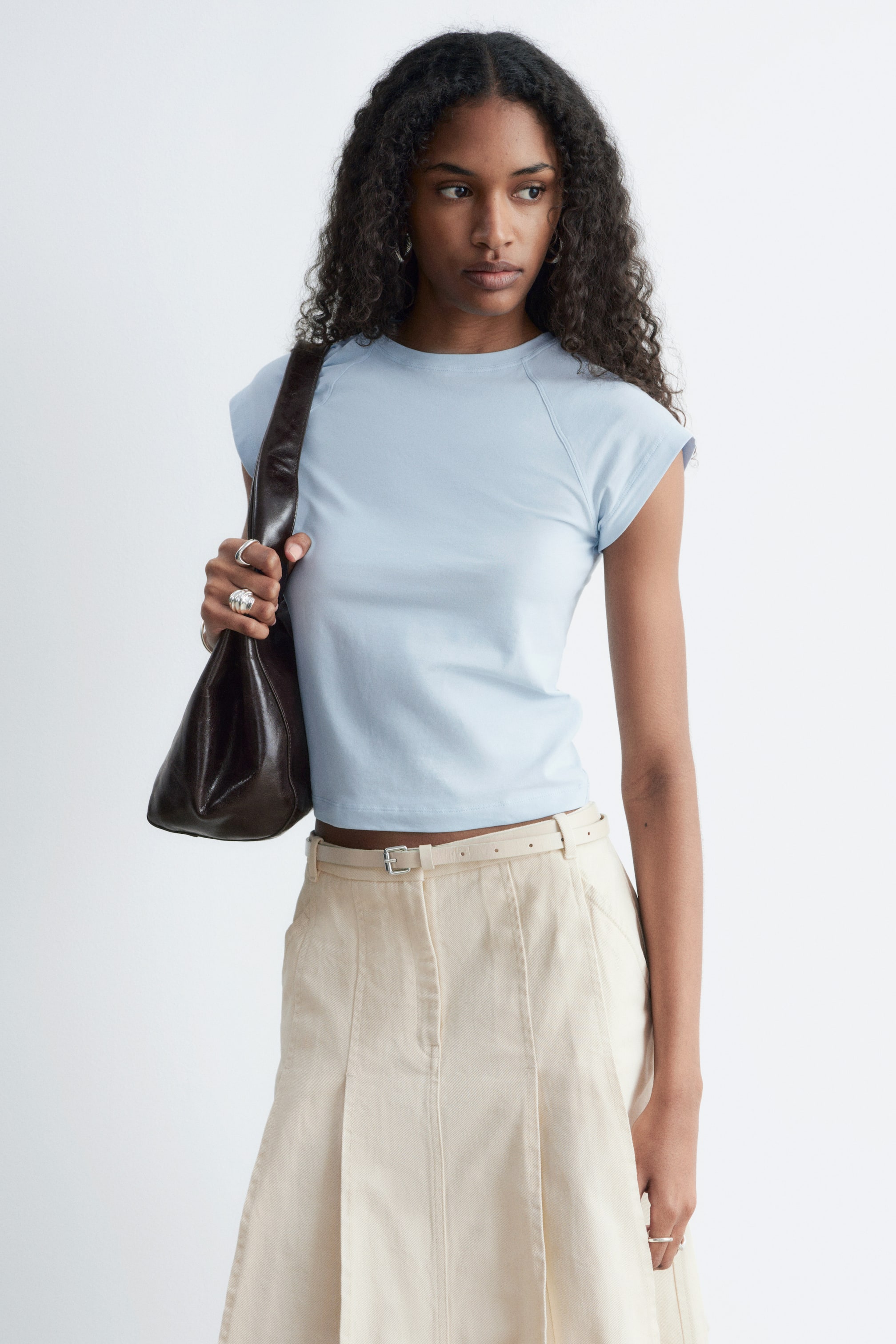 Grösseres Bild ansehen: Ein hellblaues T-Shirt mit Rundhalsausschnitt, Raglan-Kappenärmeln und einer leicht verkürzten Länge mit geradem Saum.